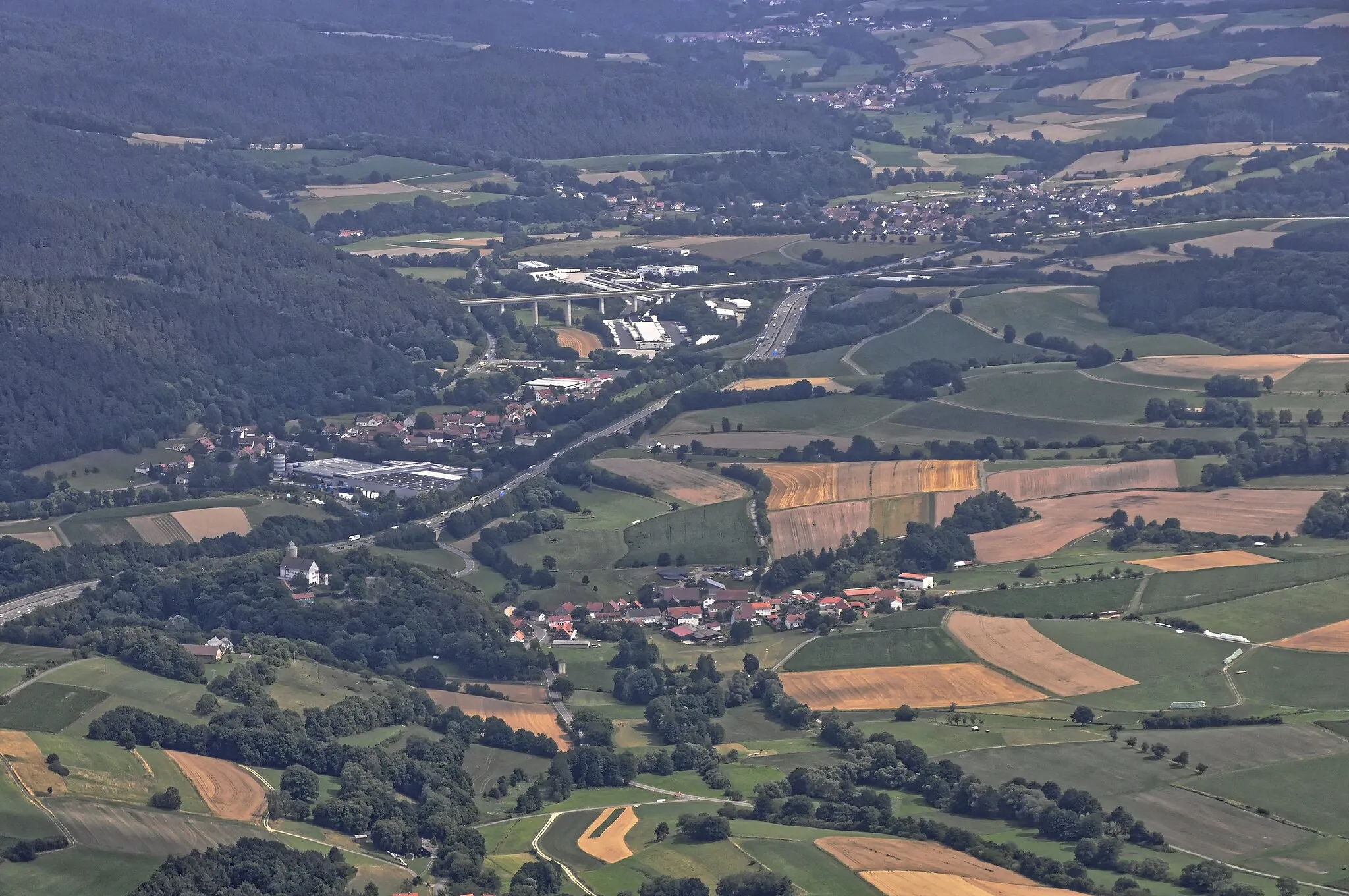 Photo showing: Bilder vom Flug Nordholz-Hammelburg 2015: In der Bildmitte vorn Saasen und links davon hinter der Autobahn A 7 Aua; dazwischen die Autobahnausfahrt 85 Bad Hersfeld unmittelbar neben der Burg Neuenstein. In der Bildmitte hinten die Geisbachtalbrücke der ICE-Schnellfahrstrecke Hannover–Würzburg über die Autobahn und die Bundesstraße B 324; rechts dahinter Obergeis im Geisbachtal.