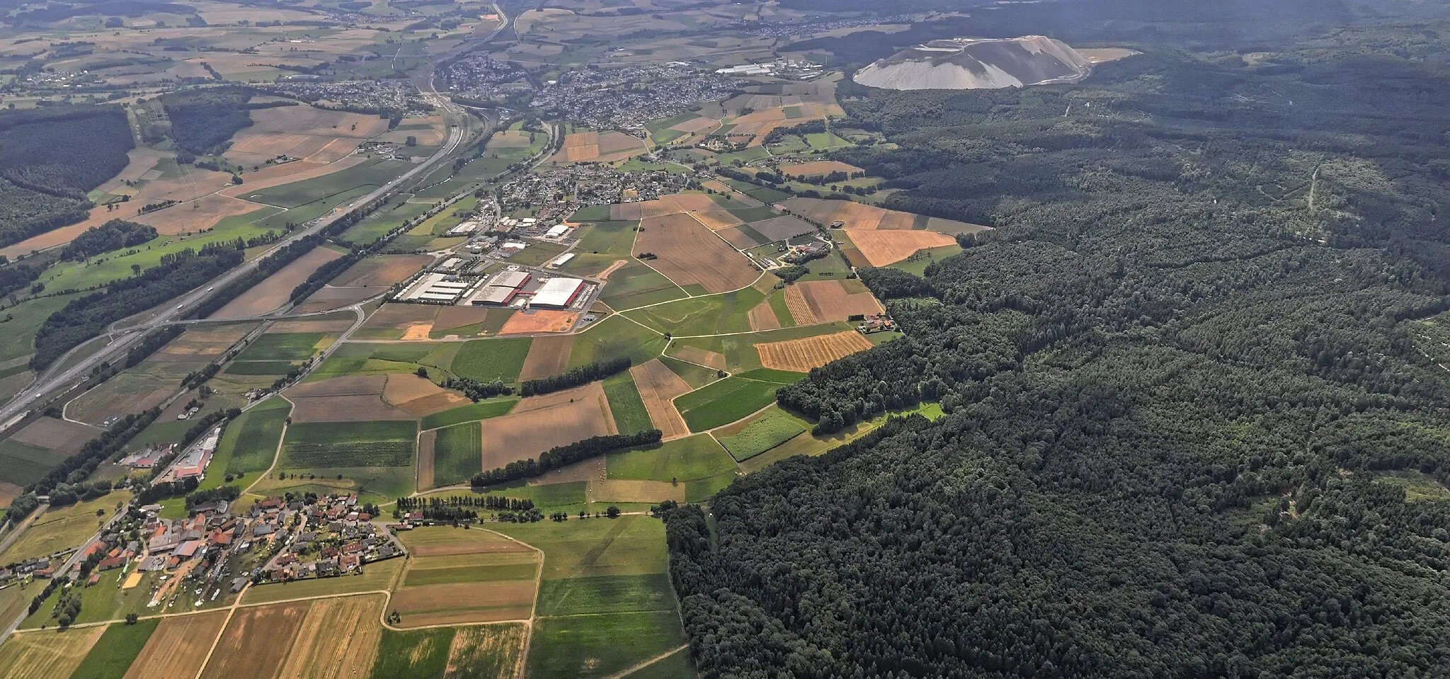 Photo showing: Bilder vom Flug Nordholz-Hammelburg 2015: Blick von Norden auf Tiefengruben (vorn), Dorfborn (Mitte) und Neuhof bei Fulda (hinten); hinten rechts die Kalibergbauabraumhalde "Monte Kali" der K + S AG. Links die Autobahn A 66 von Fulda nach Hanau und Frankfurt.