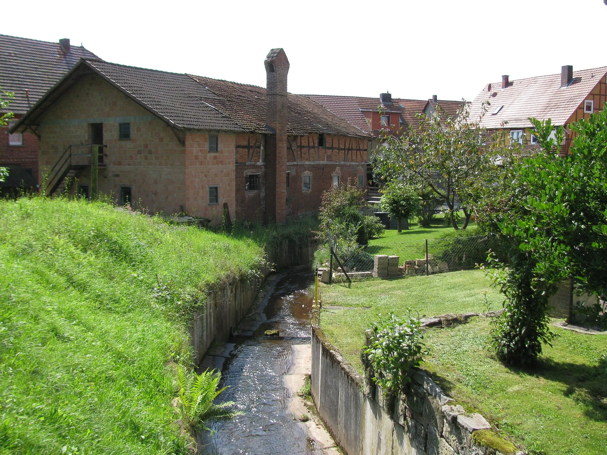 Photo showing: Zwischen der Straße Am Mühlbach und der Mühle ist der Mühlbach mit Betonplatten kanalisiert worden