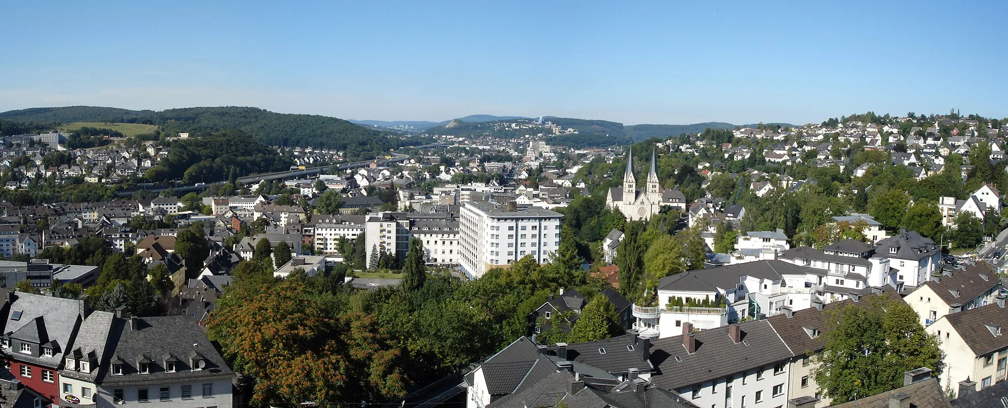 Photo showing: View from the platform of Oberes Schloss towards the northern city area of Siegen, Germany. Left: Wellersberg and the municipal's Autobahn (Hüttentalstraße, HTS). Middle: the Federal Highway (Bundesstraße) 62 and in the background the Haardter Berg with the buildings of the university.