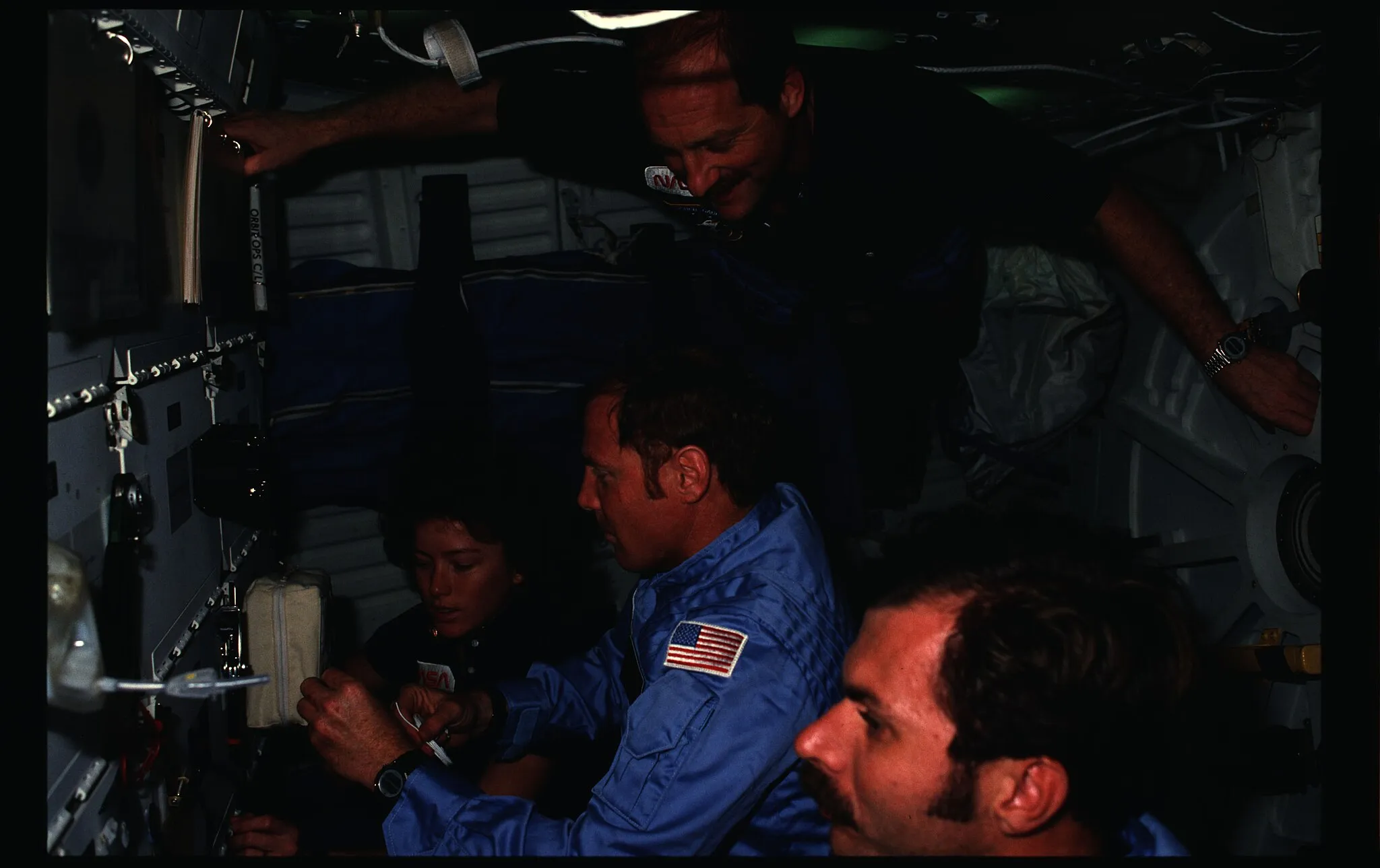 Photo showing: The original finding aid described this as: Description: Photographic documentation showing 51A crew activities. View of Commander Frederick H. Hauck, Pilot David M. Walker, Mission Specialist (MS) Anna L. Fisher and MS Dale A. Gardner on the middeck (MDDK). Subject Terms: ASTRONAUTS, CREWS, ONBOARD ACTIVITIES, SPACE SHUTTLE MISSION 51-A, DISCOVERY (ORBITER) Categories: Crew Activities Interior_Exterior: Interior Ground_Orbit: On-orbit Element: Shuttle Middeck Original: Film - 35MM CN Preservation File Format: TIFF