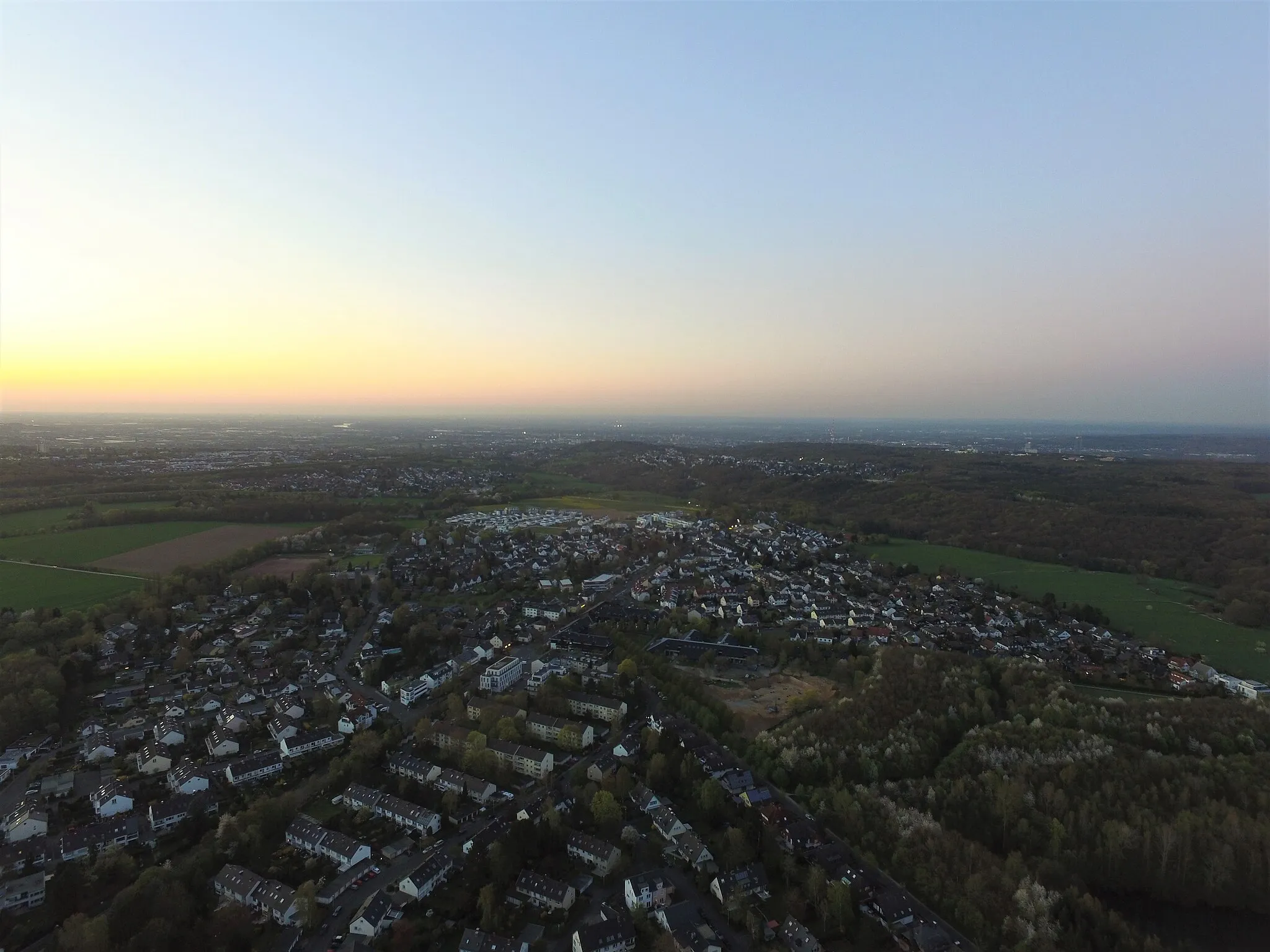 Photo showing: In der Entfernung ist Bonn zu sehen. Mittig ist die Baustelle des Campus Kottenforst zu erkennen. Die weißen Gebäude am Ortsausgang stellen das Neubaugebiet „Am Hölder“ dar.