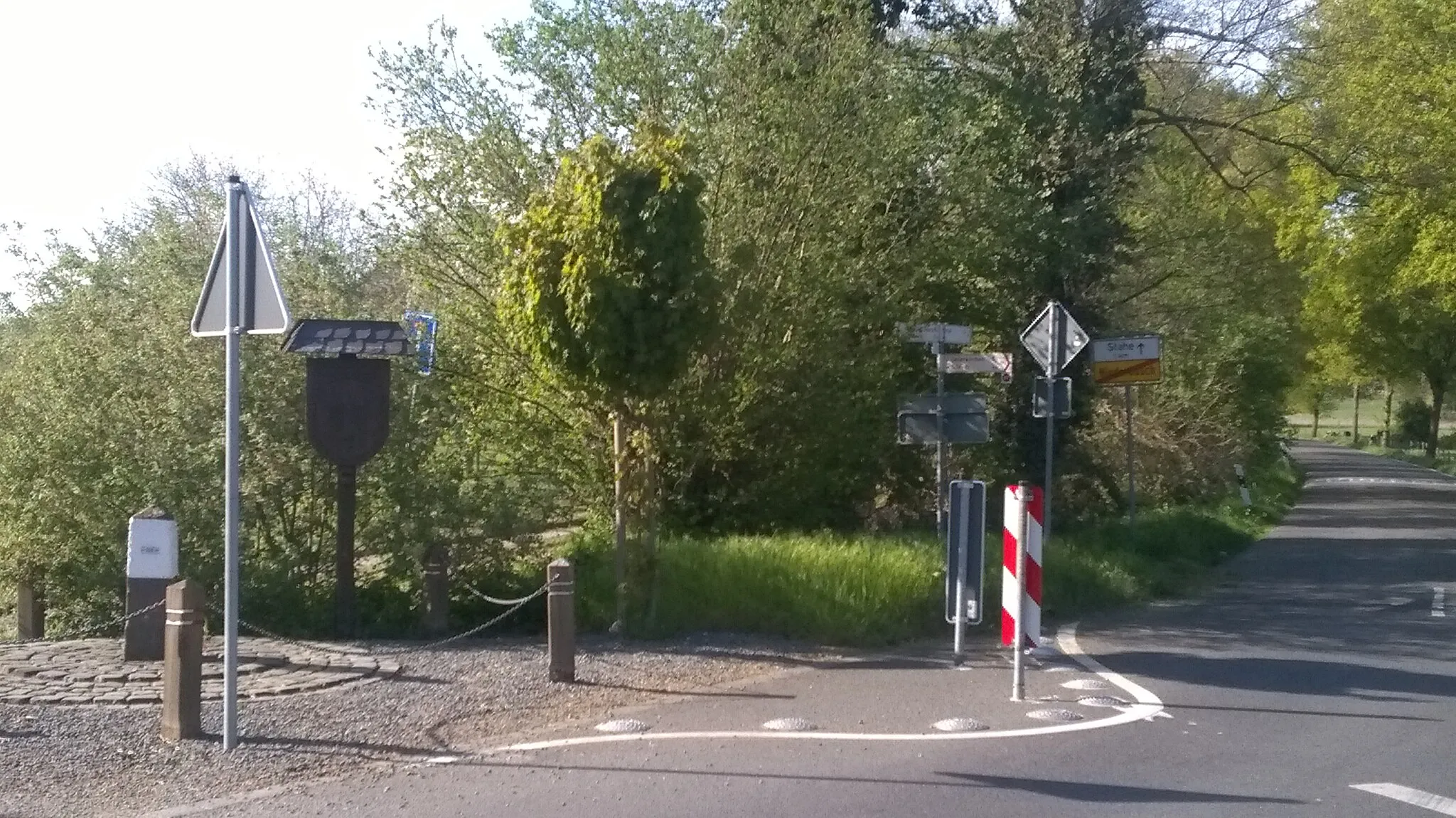 Photo showing: Rechts kijken we de weg An der Venn in. Links op de foto staat grenspaal 266 van de grens tussen Nederland en Duitsland. Op de houten paal ernaast staat het opschrift: GRENZTREFF HERINGBOS - NIEDERBUSCH 5 09 1999 en twee wapens in houtsnijwerk. Rechts van het midden staat een fietswegwijzer. Links van de weg erachter staat het bord met Stahe 1km en einde Niederbusch.