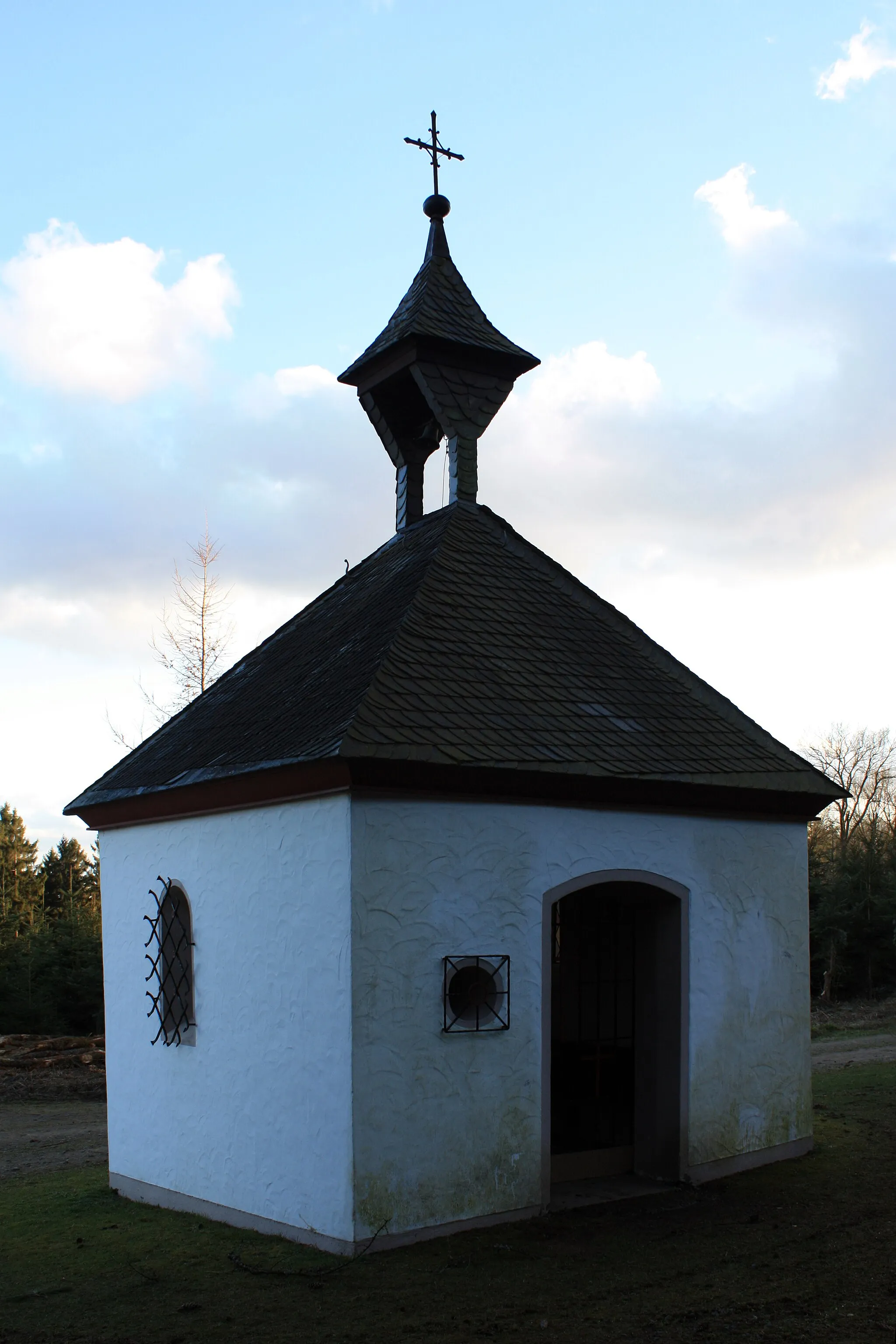 Photo showing: Kapelle St. Antonius von Padua zwischen Holpe und Flockenberg. Die Antoniuskapelle ist ein quadratischer Bruchsteinbau mit abgewalmtem Schieferdach und zwei Rundbogenfensterchen aus dem 17. Jahrhundert. Baudenkmal der Gemeinde Morsbach auf der Grundlage des Denkmalschutzgesetzes Nordrhein-Westfalen (DSchG NRW). (IMG 6057)