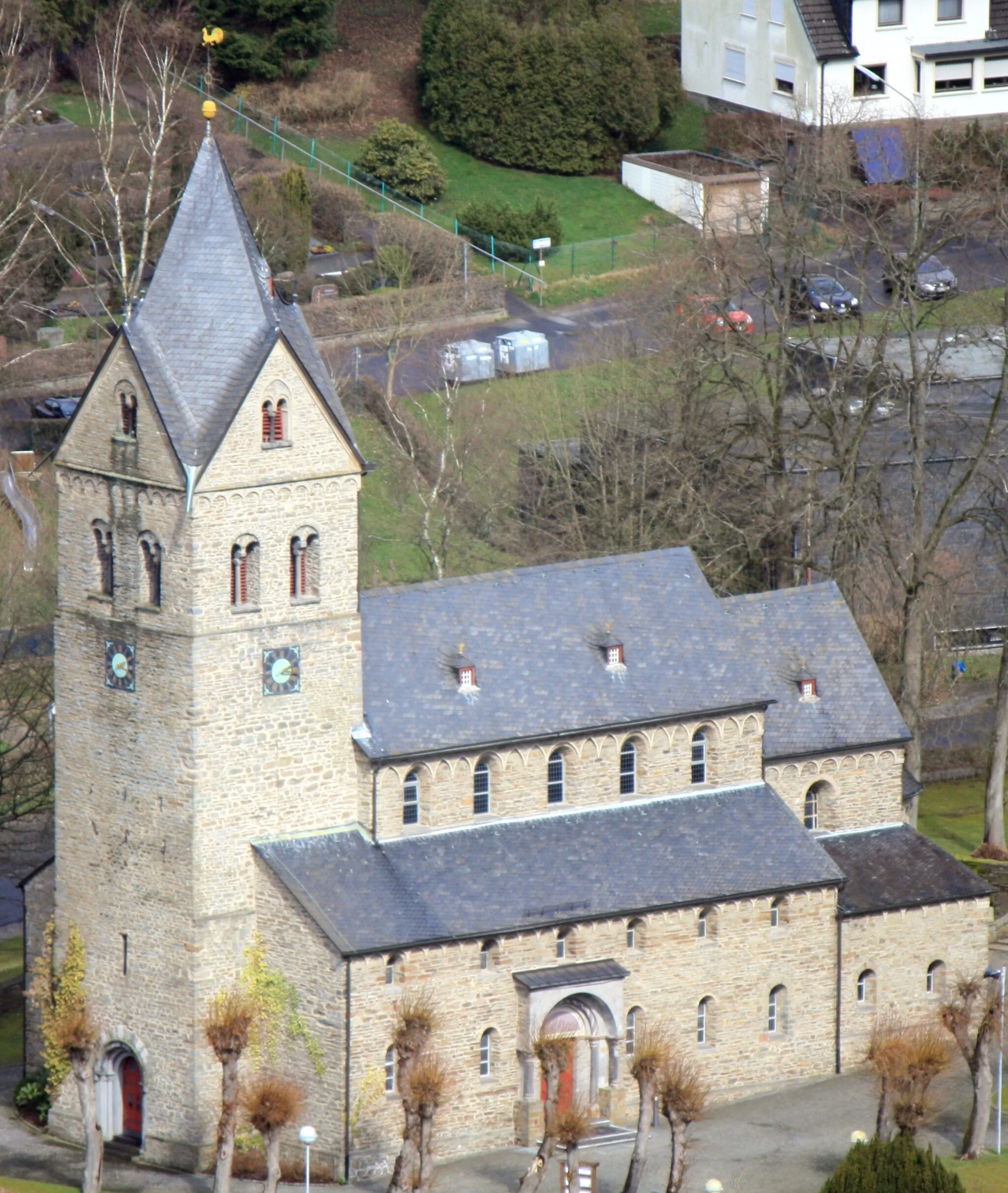 Photo showing: 3 schiffige staufisch-romanische Emporenbasilika Sankt Gertrud in Morsbach. Denkmalgeschützte katholische Kirche aus der 1. Hälfte des 13. Jahrhunderts mit vorgelagertem Westturm (31 m hoch, aus Bruchstein gemauert) vermutlich aus dem 12. Jahrhundert. (IMG 5598, die Aufnahme wurde vom Aussichtsturm Morsbach auf dem Gipfel der "Hohen Hardt" gemacht.)