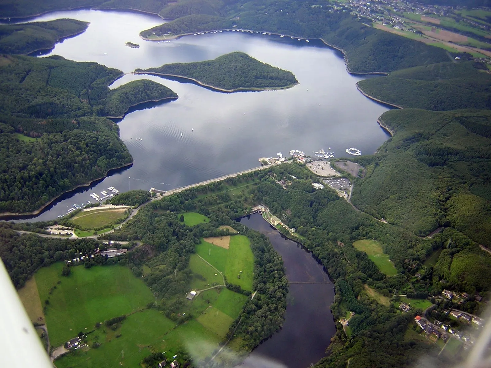 Photo showing: Luftaufnahme von „Rurtalsperre Schwammenauel“ (Staudamm) und „Rurstausee“ mit:

Halbinsel am Tonsberg (linke Bildmitte)
Insel Eichert (Bildmitte)
Halbinsel Eschauel (hinten rechts)
die Halbinsel hinten links trägt die Flurnamen „Auf dem Schlitt“ und „Morschauerheid“