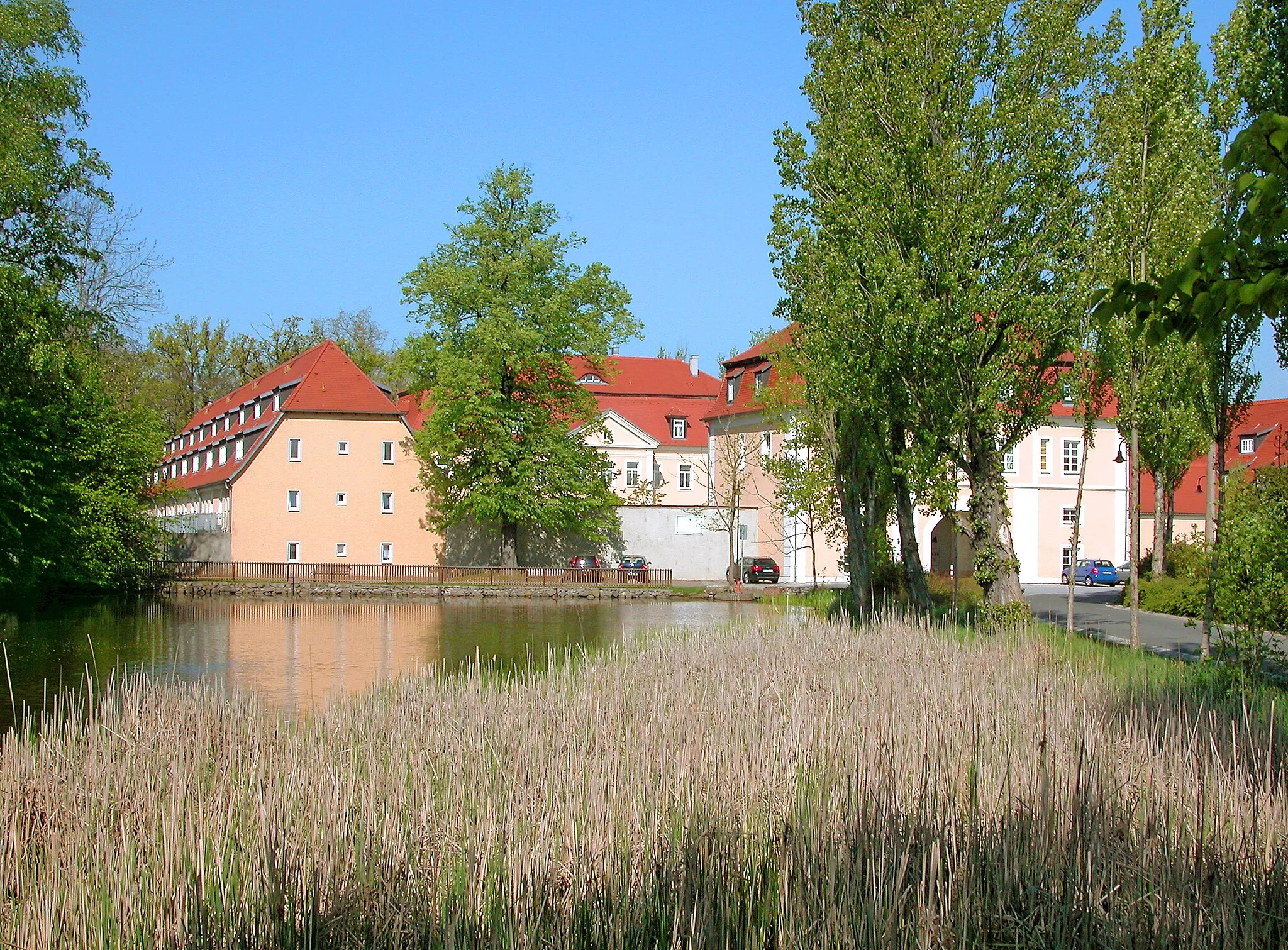 Photo showing: 25.04.2009   04683  Ammelshain (Naunhof bei Grimma), Am Schloß 1 (Pappelallee): Schloß Ammelshain (GMP: 51.295035,12.635863). Das Rittergut Ammelshain ist vermutlich aus  einem Vorwerk des Ritterguts Polenz hervorgegangen. Dieses befand sich mindestens seit dem 15. Jahrhundert im Besitz der Adelsfamilie von Lindenau. Adam Friedrich von Lindenau ließ 1723 das barocke Schloß errichten. Die Zufahrt zum Rittergutshof ist mit einem Torhaus überbaut. Das zweigeschossige Gebäude mit Durchfahrt und hohem Mansarddach wurde 1788 errichtet. Die Besitzer wechselten mehrfach. Der letzte Vorkriegsbesitzer, Major a. D. Georg Eckhardt, 1913 geadelt, wurde 1945 enteignet. 1991 kauften Prof. Dr. Alexander Riesenkampff, Dr. Peter Harff und Hellmuth Freiherr von Maltzahn das Schloß und das Rittergut und richteten Wohnungen ein. Blick vom Schloßteich.                                                                                                                                                                                                                        [DSCN36706.TIF]20090425150DR.JPG(c)Blobelt