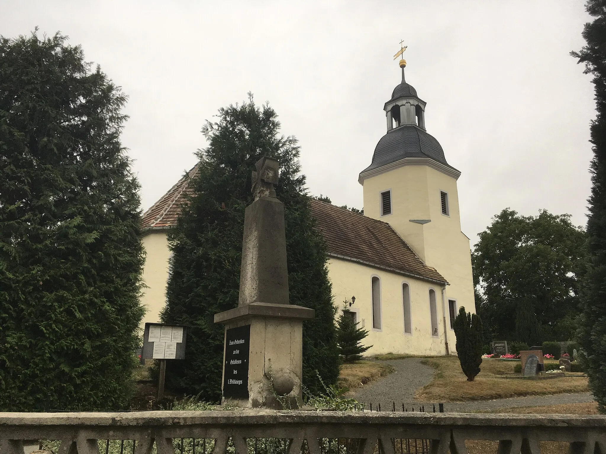 Photo showing: Village church with interior and churchyard cemetry with monument to the fallen of the First World War in Dahlenberg (Trossin), Main street (german: Hauptstraße),
single-aisled hall church: plastered quarry stone construction, gable roof, crown tail cover, basket arch window with flaps, square west tower, oktogonal-shaped in the bell floor, above hood (slate cover), lantern (zinc sheet) inscribed 1781 with segmental arch openings, ball attachment, weather vane and cross, 3/8 choir closure, inside 3-sided wooden gallery, organ gallery with openwork parapet, pulpit renewed in the 20th century (balustrades: depictions of the evangelists around 1620), commemorative plaque inscribed in 1620 (Predella depicting the sacrament and crucifixion, kneeling donor family), wooden crucifix (unmounted/early 20th century). War memorial: rectangular sandstone base, on the front inscription panel of Swedish granite, inscription: "Died the heroic death" [the names of the fallen and missing], on the back: "My people, don't forget the faithful heroes", above rejuvenating sandstone stele with inscription (illegible), attached Iron Cross, on the back of the stele relief of a steel helmet and stick grenades, lateral sandstone cannonballs on the towed pedestal; of importance for building history and local history; cultural heritage monument