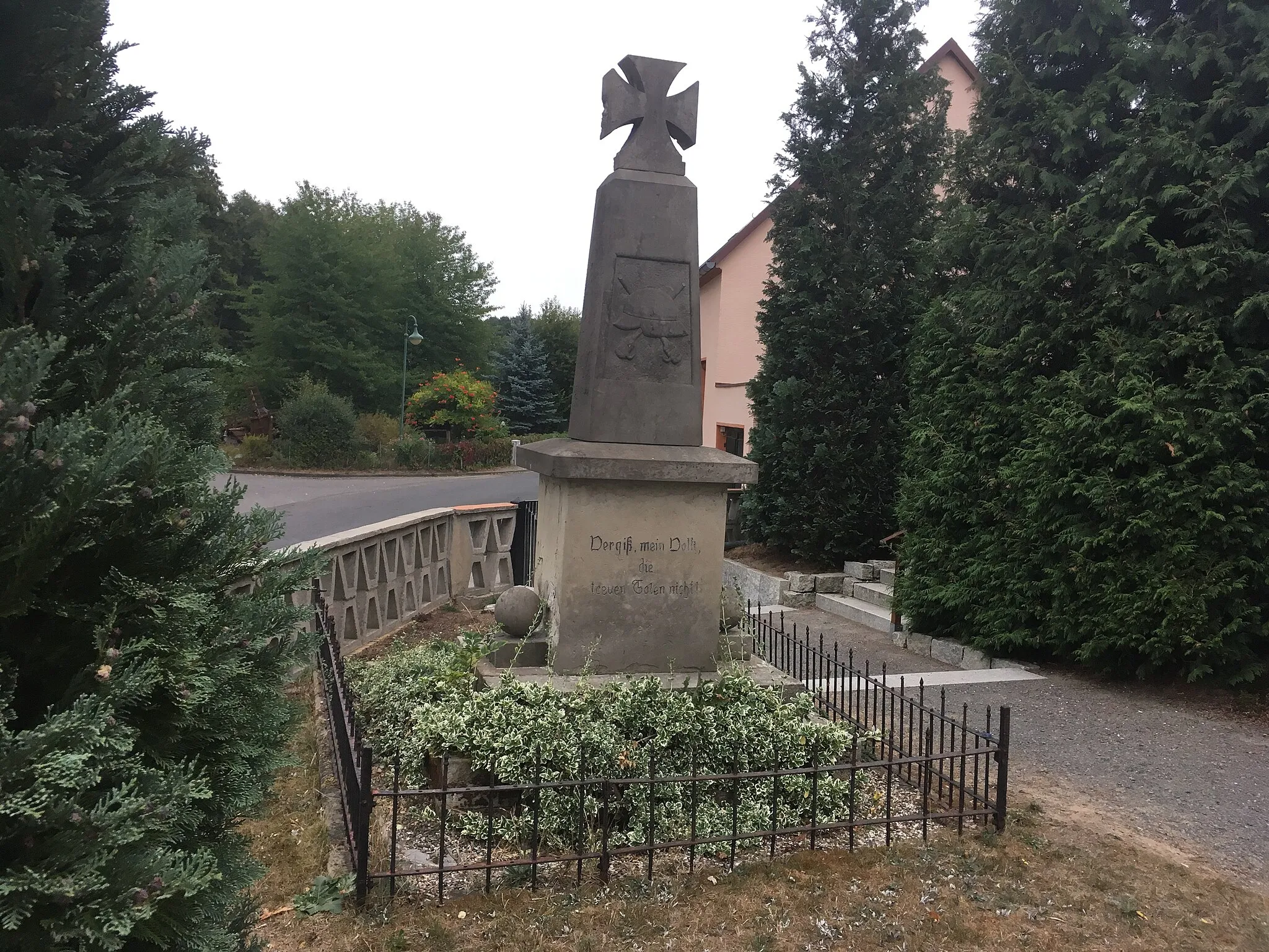 Photo showing: Memorial to the fallen of the First World War in the churchyard of the church in Dahlenberg, Main street (german: Hauptstraße), rectangular sandstone base, on the front inscription panel of Swedish granite, inscription: "Died the heroic death" [the names of the fallen and missing], on the back: "My people, don't forget the faithful heroes", above rejuvenating sandstone stele with inscription (illegible), attached Iron Cross, on the back of the stele relief of a steel helmet and stick grenades, lateral sandstone cannonballs on the towed pedestal; 
of importance for building history and local history; cultural heritage monument