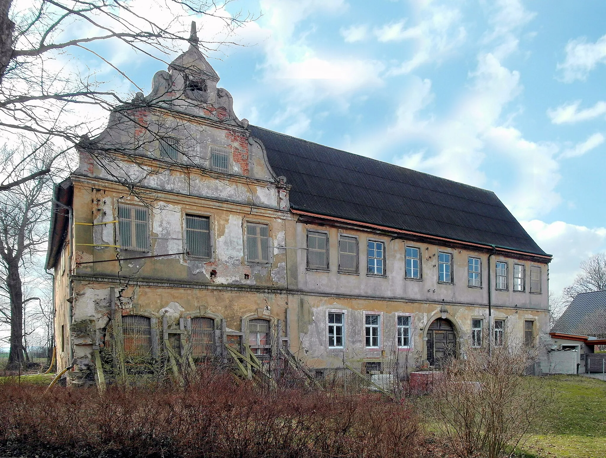 Photo showing: 12.03.2017    01561   Cunnersdorf (Ebersbach), An der Mühle: Das Herrenhaus (GMP: 51.270363,13.668863) an der Großen Röder, hier die Hofseite (Nordosten), stammt aus dem 17. und 18. Jahrhundert. 1656 baute der Rittergutsbesitzer Christian Zschimmer den mit Renaissancegiebeln verzierten östlichen Flügel (links). Noch bis 1991 war das Haus bewohnt. Danach schritt der Verfall schnell fort. Der Renaissancegiebel an der  Röder ist bereits eingestürzt. Den hofseitigen Giebel haben die neuen Eigentümer (seit 2008) notdürftig gesichert.               [SAM8367.JPG]20170312100DR.JPG(c)Blobelt