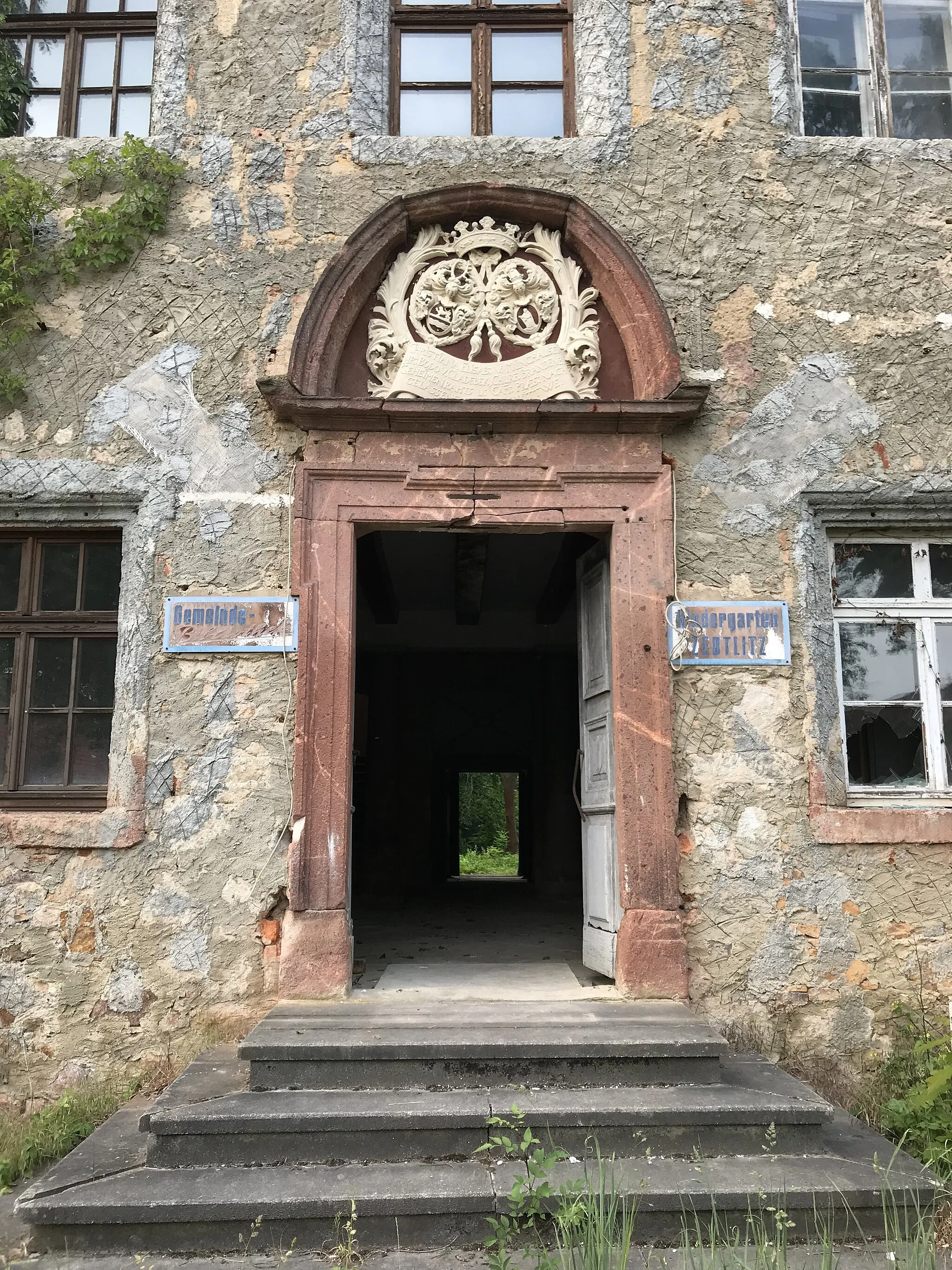 Photo showing: Erschlossen wird das Gebäude durch ein repräsentatives Barockportal in der Mitte. Es hat eine verkröpfte Rahmung mit einem Relief darüber, das über einer Inschrift die Wappen der Familien von Gladecke und von Münchhausen zeigt. Vor ihm ist eine Freitreppe angeordnet.