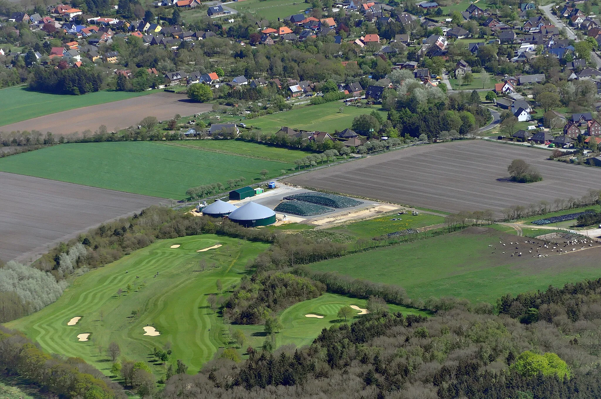 Photo showing: Luftbilder von der Nordseeküste 2012-05; Biogasanlage bei Cuxhaven-Oxstedt, rechts im Bild einzeln auf dem Feld stehend ein Hügelgrab