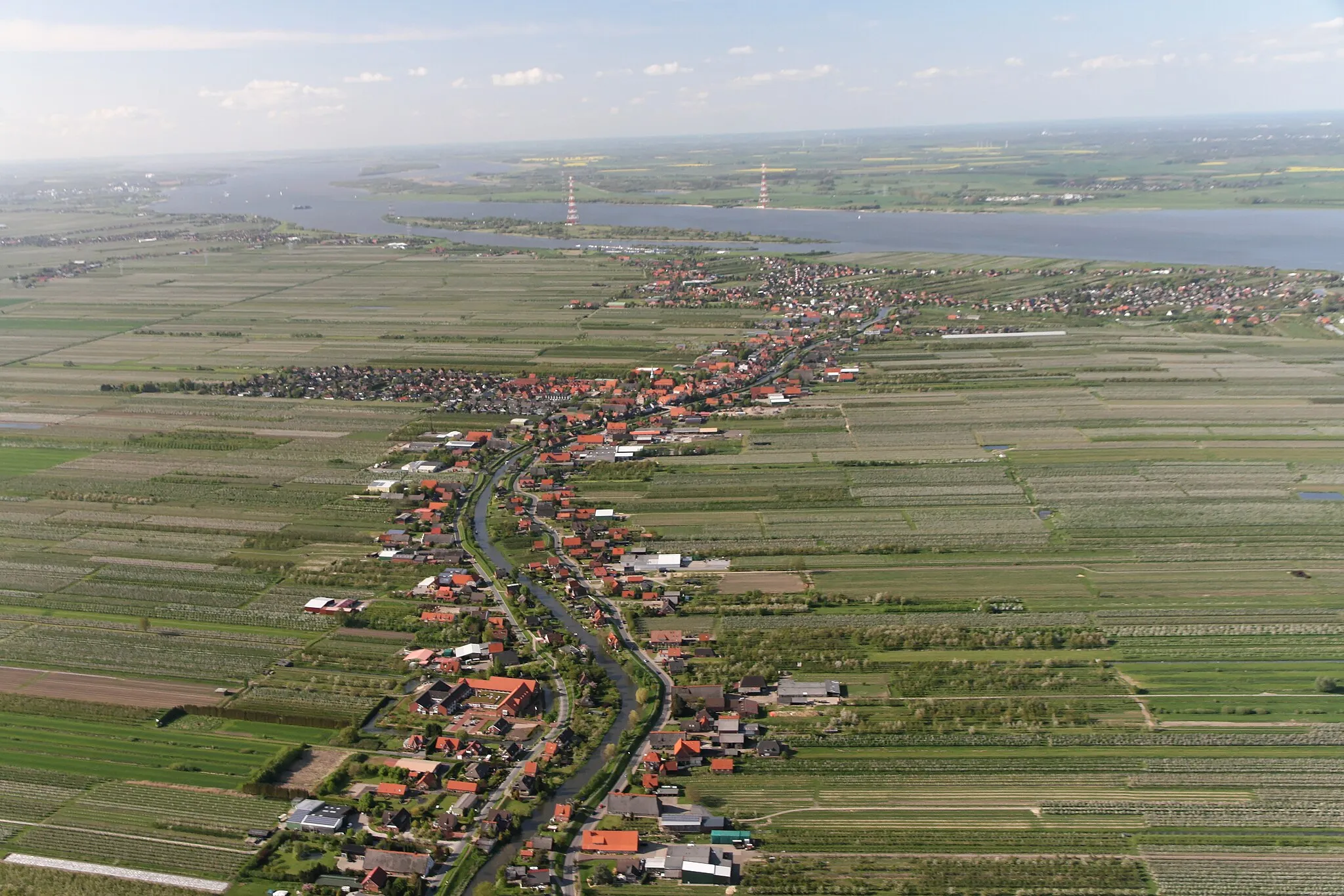 Photo showing: Luftaufnahme: der kleine Fluss, der das Bild teilt, ist die Lühe, der Ort links ist Steinkirchen, der Ort rechts ist Mittelnkirchen, der Ort vor der Elbe ist Grünendeich, in der Elbe dahinter liegt der Lühesand