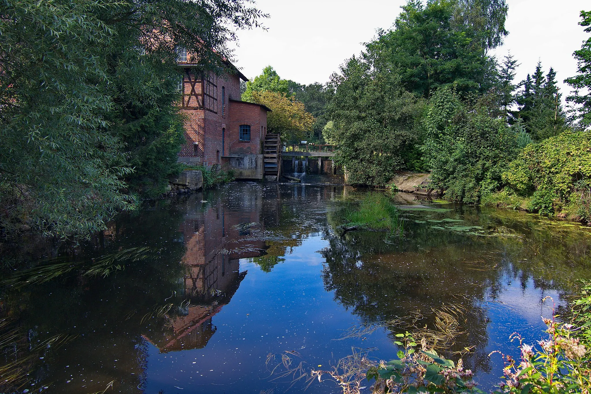 Photo showing: Das heutige Gebäude der Wassermühle in Beedenbostel an der Aschau wurde 1905 nach einem Brand auf der Vorgängermühle errichtet, die im Jahr 1649 erstmals urkundlich erwähnt und bis 1920 im Vollerwerb betrieben wurde. Heute treibt das Mühlrad einen Stromgenerator für den Eigenbedarf. In den Räumen wird u.a. ein Cafe betrieben.