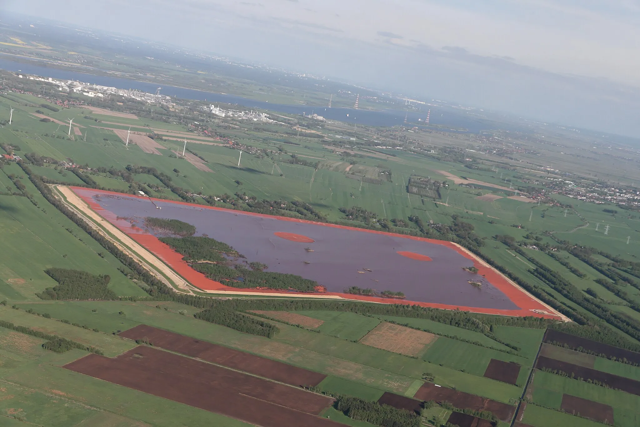 Photo showing: Blick von Westen op de Roodslammdeponie, Bützfletermoor an de Achterkant von de Deponie, ganz in'n Achtergrund de Elv mit Bützfleet, dat Industrierebeed Bützfleet (links) un Stood (rechts).