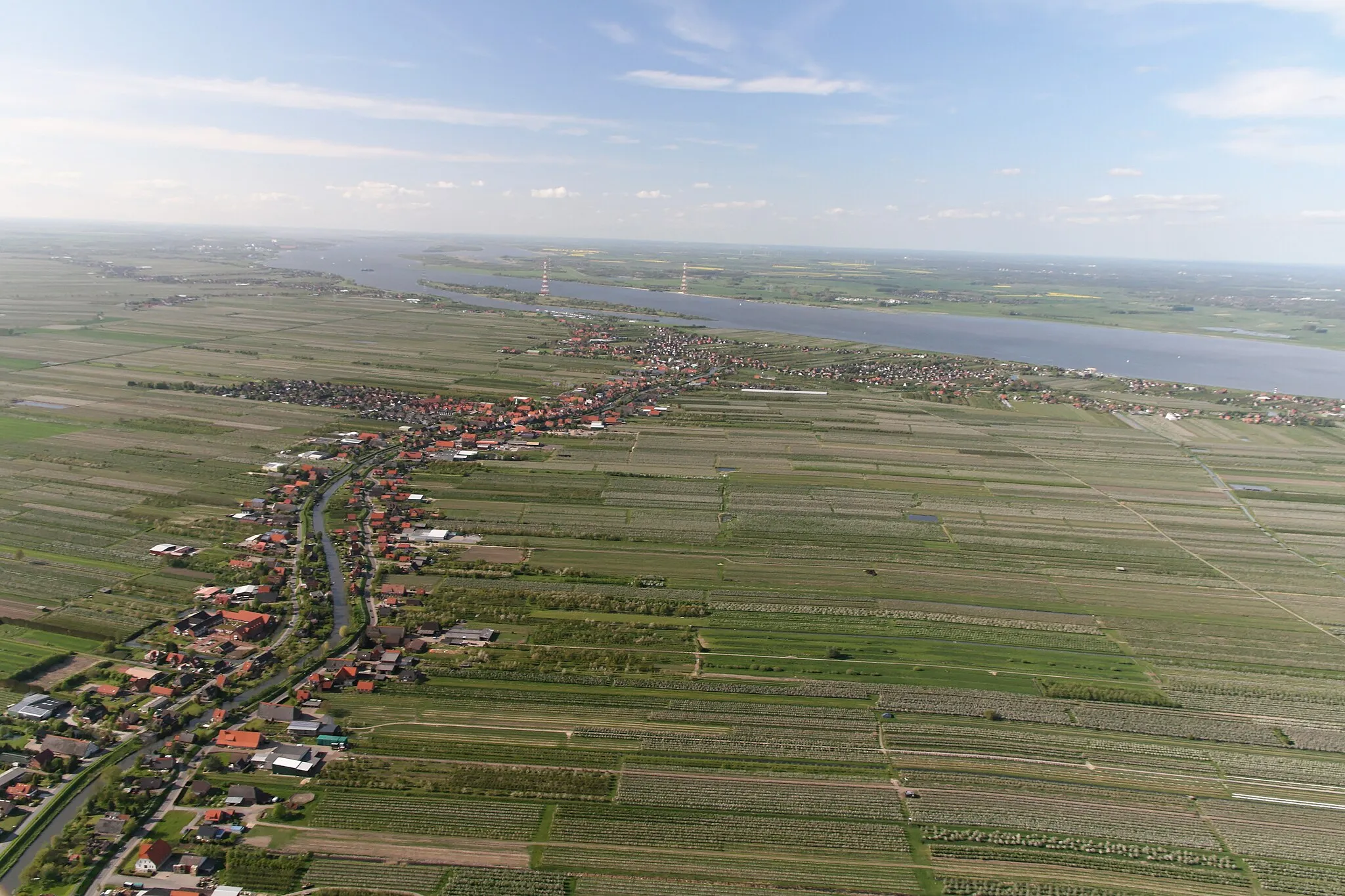 Photo showing: Luftaufnahme: der kleine Fluss, an der linken Bildseite, ist die Lühe, der Ort links ist Steinkirchen, der Ort rechts ist Mittelnkirchen, der Ort vor der Elbe ist Grünendeich, in der Elbe dahinter liegt der Lühesand