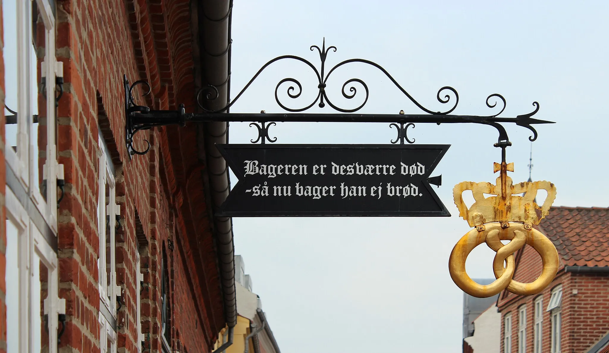 Photo showing: The well known sign on Zahrtmanns Gård, Sct. Mogens Gade 26, Viborg, Denmark from 1972 or 1973. The text translates to "The baker is unfortunately dead - so now he is not baking bread" and originates from the Danish author Peter Seeberg.