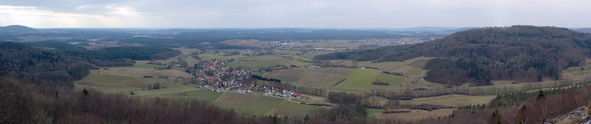 Photo showing: A panorama from the Glatzenstein, a hill in the Franconian Jura in northern Bavaria. In the center the village of Kersbach can be seen and behind it, Rollhofen. To the right, partially obscured by a hillside, is Schnaittach. To the left, behind a forest, lies Speikern. Even further to the left and behind it is Ottensoos. The hill to the right is Rothenberg on top of which Rothenberg Castle can be seen.