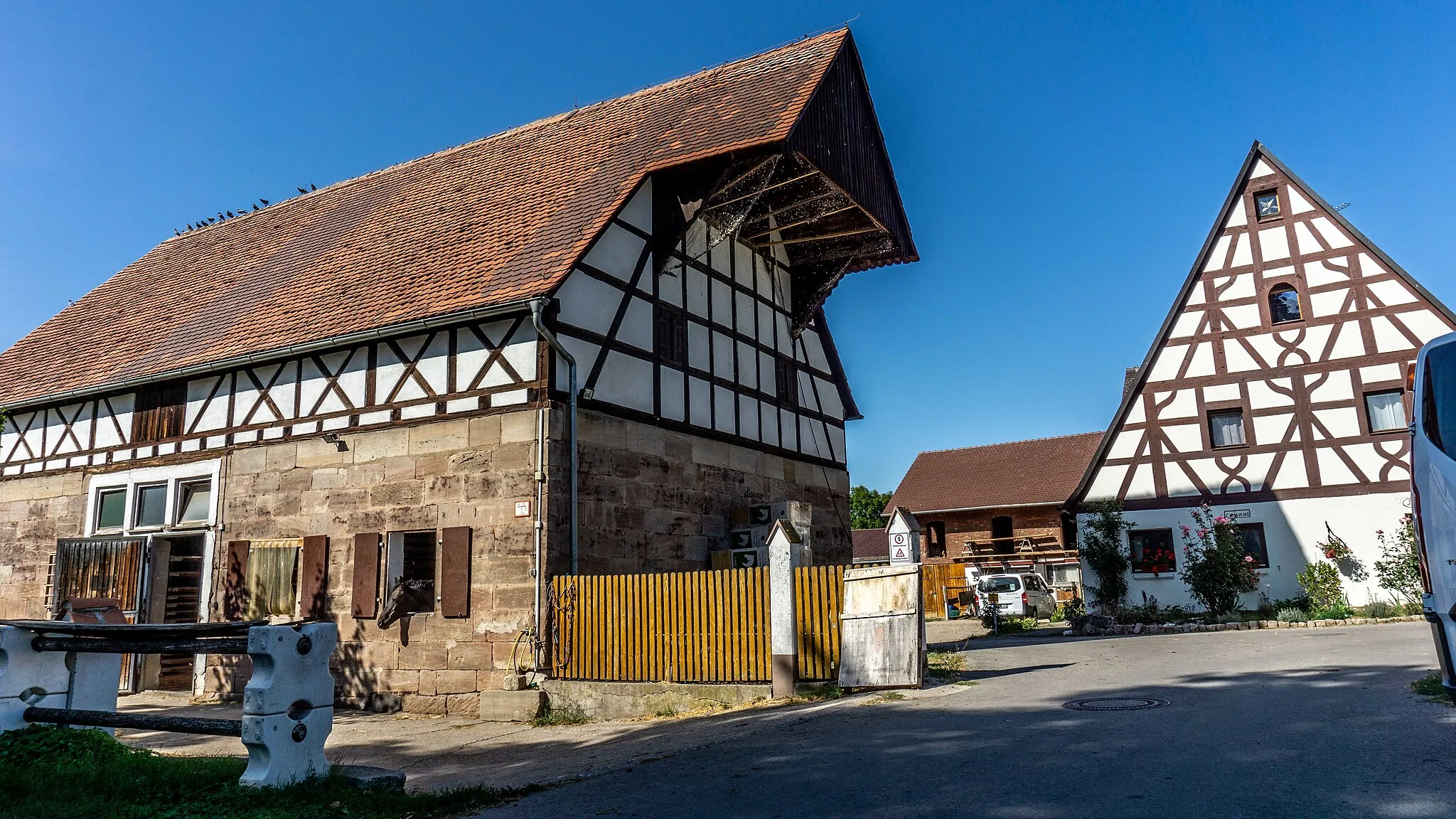 Photo showing: Wohnstallhaus, eingeschossiger freistehender Satteldachbau, verputzter Sandsteinquaderbau mit Sichtfachwerkgiebel, bezeichnet mit 1783, Schleppgauben modern
Austragshaus, erdgeschossiger Sandsteinquaderbau mit Steildach, frühes 19. Jahrhundert

Scheune, zweigeschossiger freistehender Satteldachbau mit weit vorkragendem Aufzugsdach, Sandsteinquaderbau mit Sichtfachwerkobergeschoss und -giebel, wohl 19. Jahrhundert