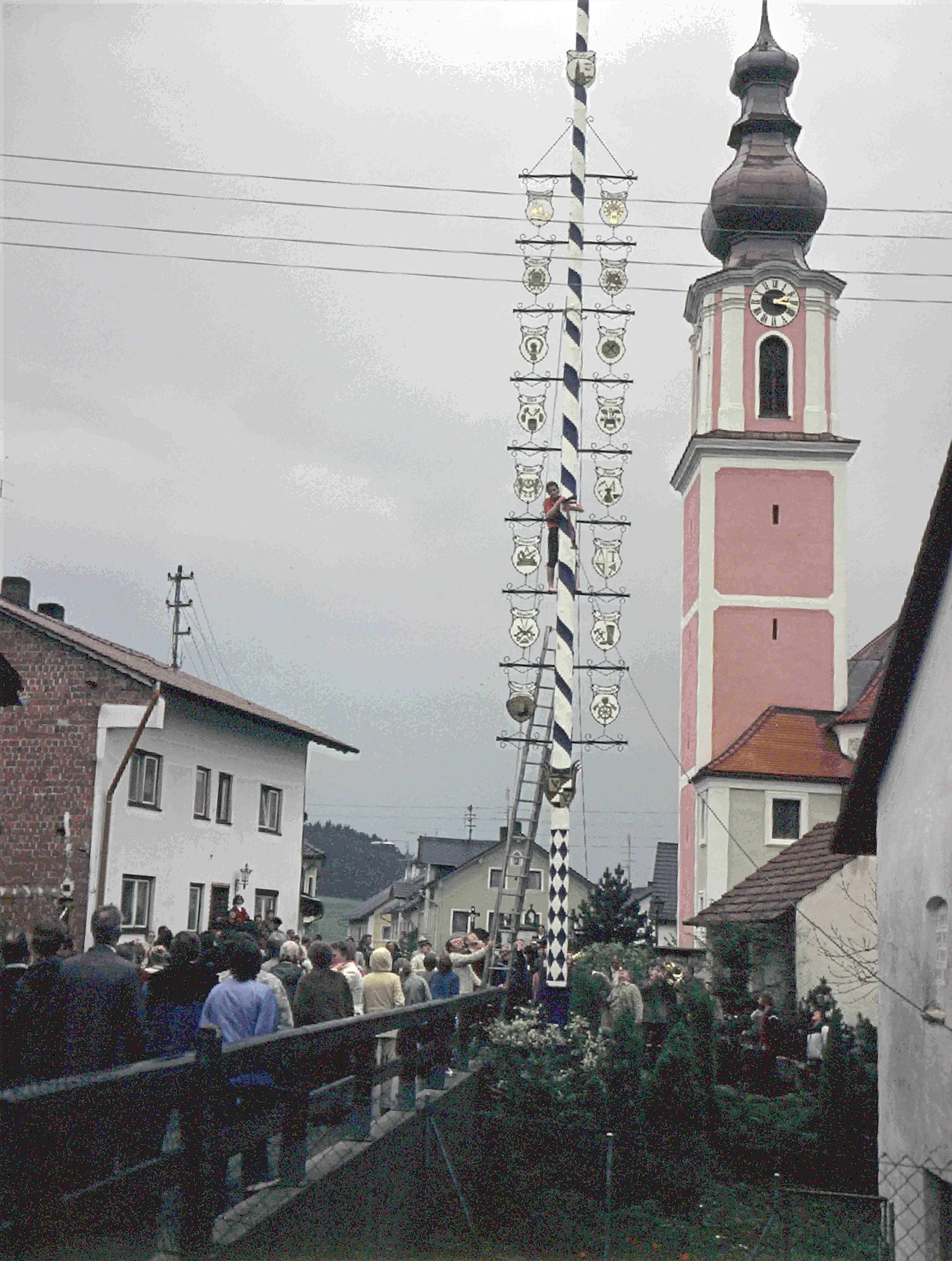 Photo showing: Haunzenbergersöll Maibaum 1982 1. Mai Kraxeln Maifeier Kirchturm Kirche St. Johannes der Täufer Menge Zunftschilder