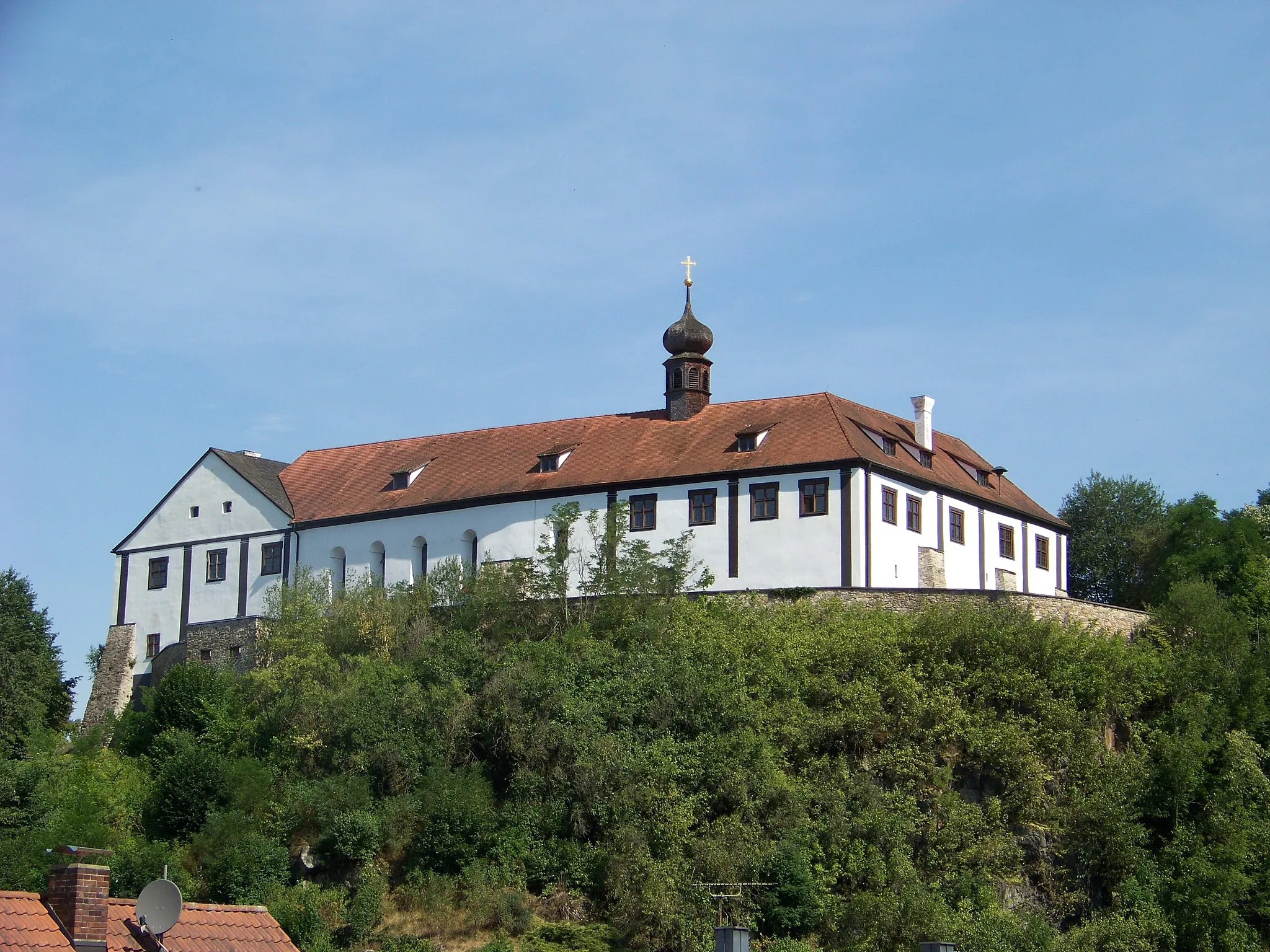 Photo showing: Altrandsberg, Schloßweg 1, Schloss, zweigeschossige Vierflügelanlage um trapezförmigen Innenhof mit gewölbter Tordurchfahrt und teilweise schindelgedecktem Walm- und Satteldächern, im 17. Jahrhundert unter Einbeziehung von Teilen der mittelalterlichen Wehrmauerabschnitte, des Bergfrieds und des Palas ausgebaut, Erneuerungen und Umbauten nach Bränden im 16./17. Jahrhundert, Westflügel 1950 weitgehend neugebaut, 1895- 1973 Nutzung als Gemeindekanzlei und Schule, im Südflügel ehem. Schlosskapelle St. Michael mit verschindeltem Zwiebeldachreiter, ursprünglich rippengewölbt, in der 1. Hälfte 18. Jahrhundert umgestaltet und in den 1930er Jahren als Filialkirche erweitert; mit Ausstattung; Reste der Befestigungsanlage, Bruchsteinmauerwerk, Granit; Schlosstor, Rundbogen mit Keilstein und Kämpfern, bez. 1853.