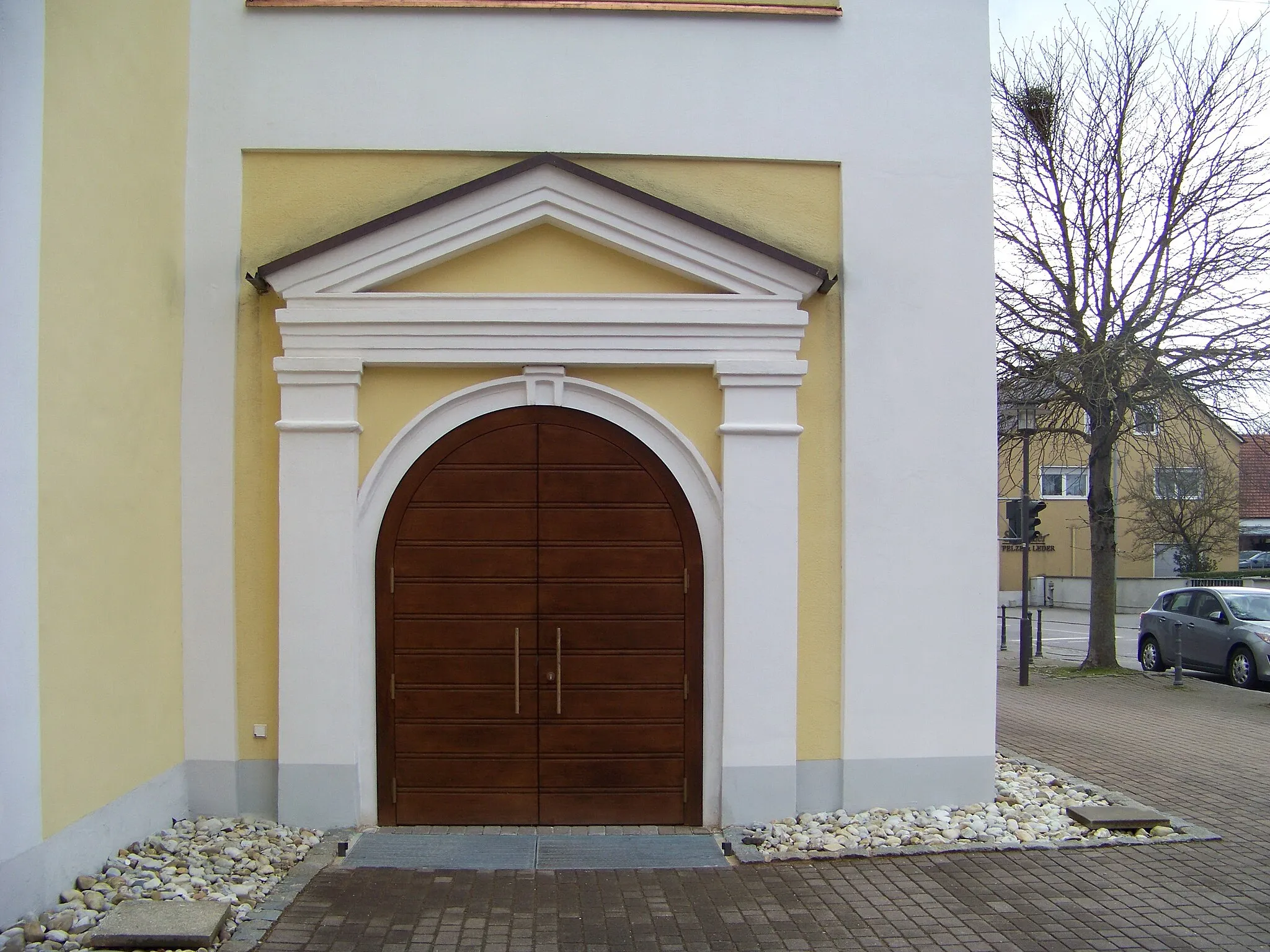 Photo showing: Ergoldsbach, Hauptstraße 18. Katholische Pfarrkirche St. Peter und Paul. Saalkirche mit erweitertem Querhaus und Westturm, erbaut 1729, Chor und Querhaus 1886/87, Gliederung durch Lisenen und Dachfries sowie Putzbänderung. 
Westturm mit Geschossgliederung, abgesetztem Oberbau und Spitzhelm. Portal an der Nordseite des Turmes.