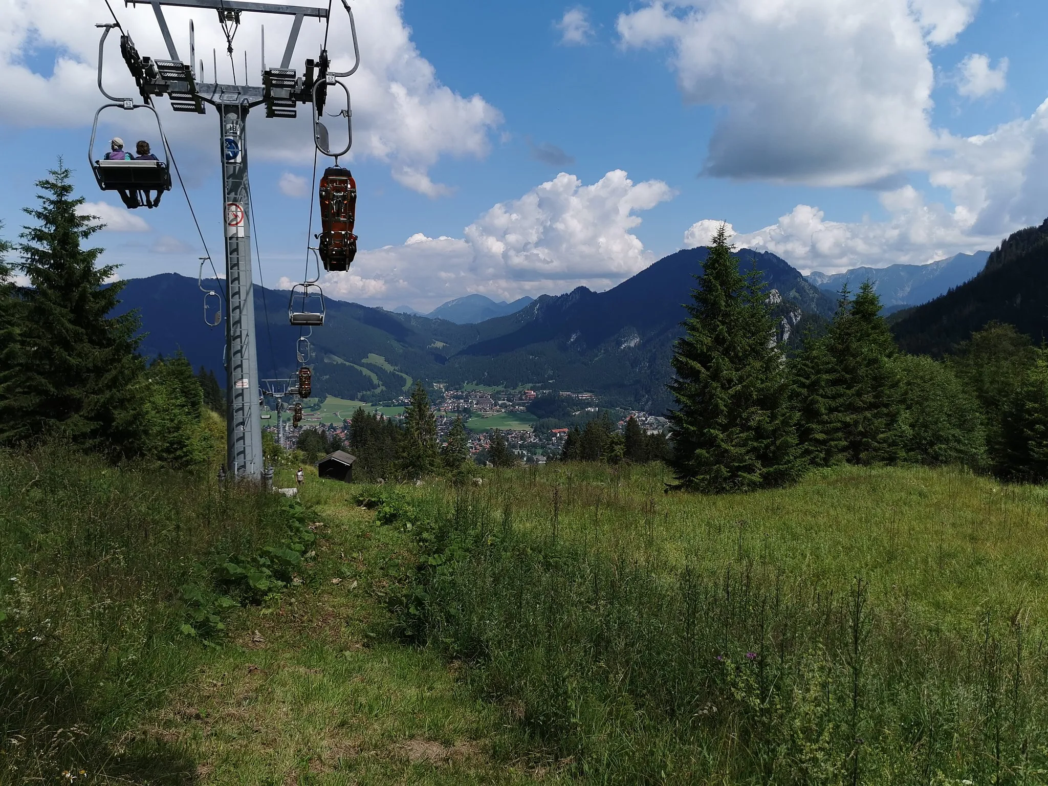 Photo showing: Hochförderung einiger AlpineCoaster-Fahrzeuge über die Sesselbahn auf den Kolbensattel. Unten im Tal Oberammergau mit dem Berg Laber auf der anderen Talseite. Etwas versteckt hinter den Bäumen der nahegelegene Felsgipfel und Aussichtspunkt Kofel.