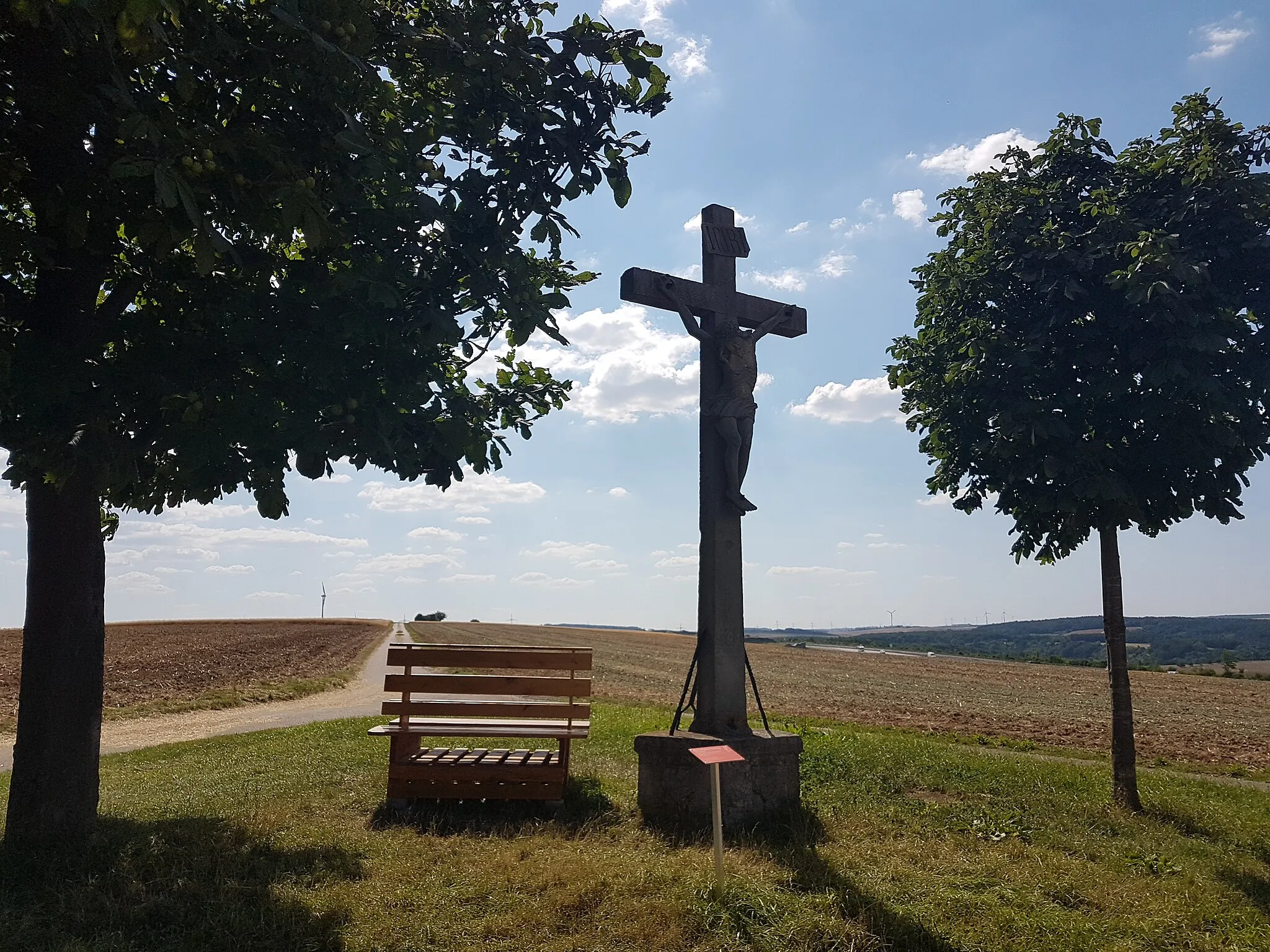 Photo showing: Standort siehe Karte (Permalink) bei udo.lubw.baden-wuerttemberg.de.
Das Wetterkreuz wurde 1714 zum „ewigen Andenken“ an einen großen Gewitterschaden errichtet und ist heute auf vielen Wanderkarten ausgewiesen. Sein Postament bildete den Grenzstein zu den ehemaligen Gemarkungen der fünf Altgemeinden (Distelhausen, Dittigheim, Dittwar, Lauda und Oberlauda), deren Ortswappen darauf abgebildet sind. Nach der Gebietsreform in Baden-Württemberg sind die angrenzenden Altgemeinden teils nurmehr Ortsteile und Dittigheim ist nicht mehr unmittelbarer Anlieger. Das Wetterkreuz wurde von einem Grünsfelder Bildhauer geschaffen. Im Jahre 1849 erfolgte eine Renovierung des Wetterkreuzes. Nachdem einer der beiden Kastanienbäume, die das Wetterkreuz einrahmen, einen Sturm im Jahre 2011 nicht überstanden hatte, wurde an der gleichen Stelle ein neuer Kastanienbaum gepflanzt.