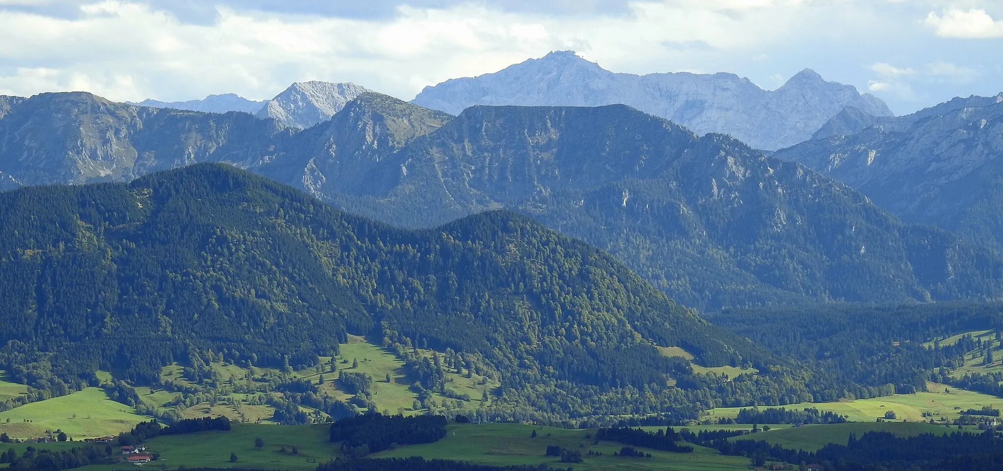 Photo showing: Ammergebirge von Nordwesten mit Firstberg und Grubenkopf; der bewaldete Firstberg sieht auch aus wie der Name sagt, gerade wie ein Dachfirst. Das graue Wettersteinmassiv im Hintergrund.