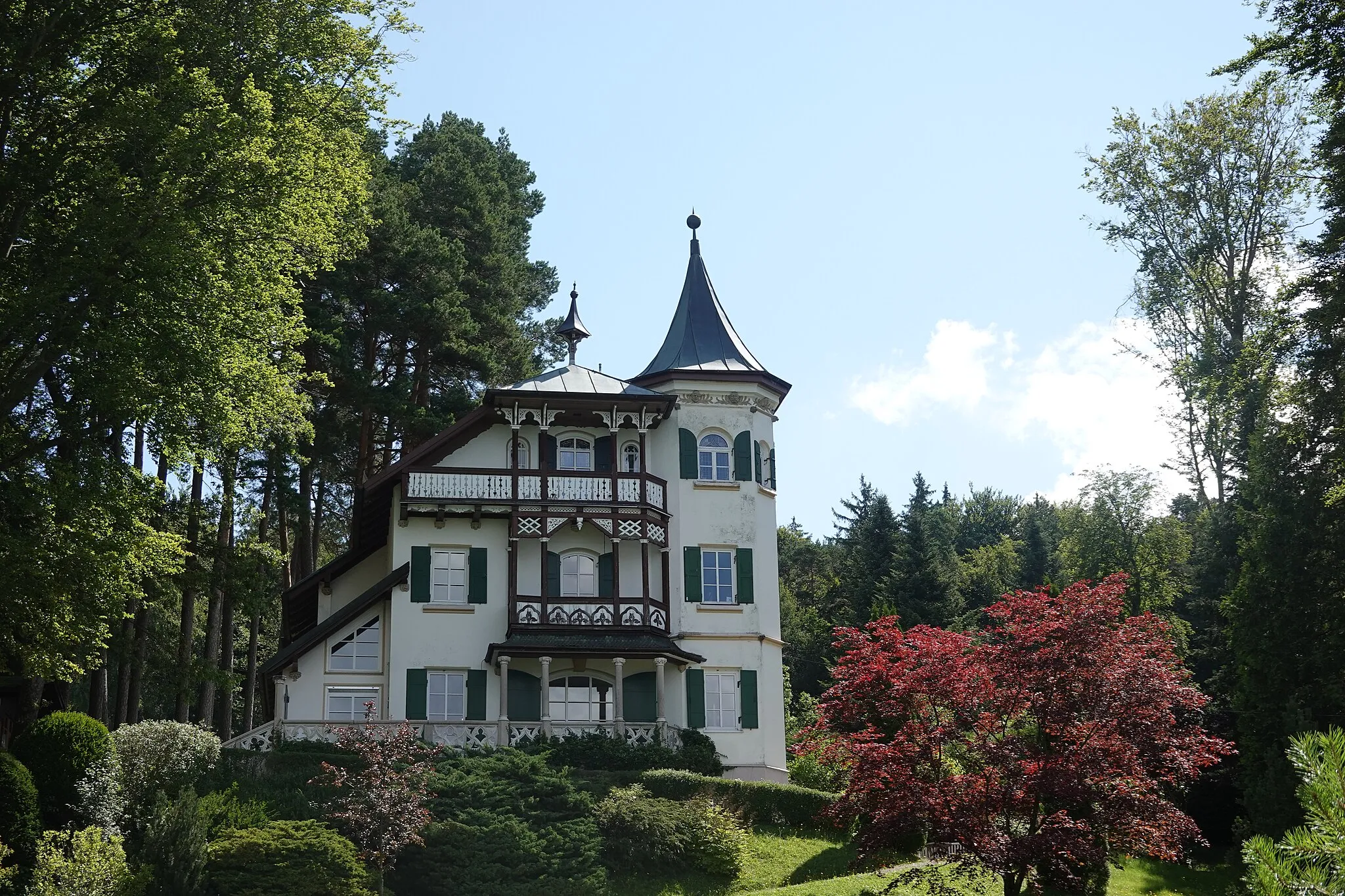 Photo showing: Zweigeschossiger Schopfwalmdachbau in historisierenden Heimatstilformen mit Zeltdach-Eckturm, Zierfachwerk-Veranda, Balkons, Glockenstuhl und plastischem Dekor, 1900.