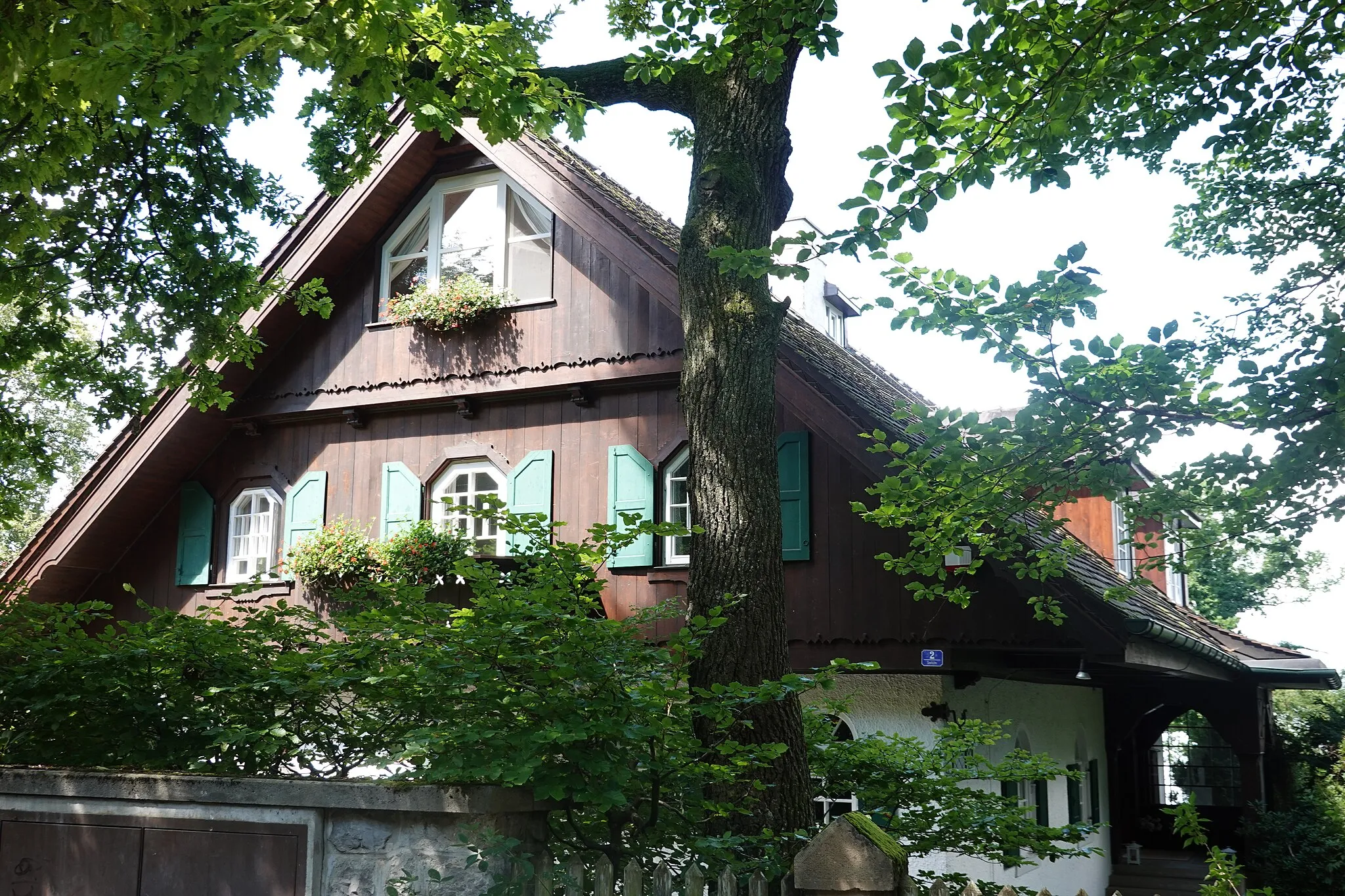Photo showing: Erdgeschossiger Satteldachbau mit weitem Vordach, Runderker, Rundbogenfenstern und Veranda, Anfang 20. Jahrhundert