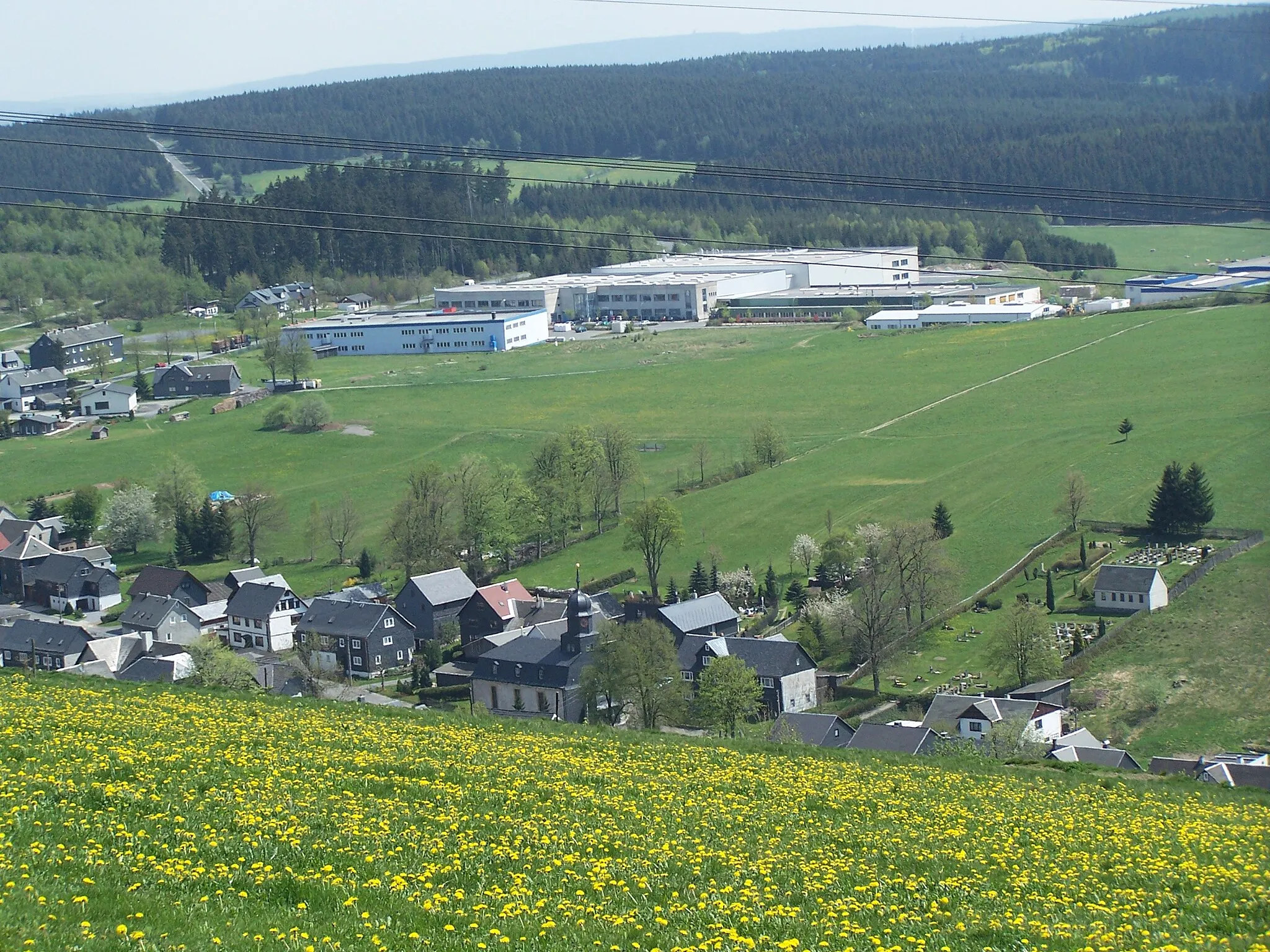 Photo showing: Das Rennsteigdörfchen Spechtsbrunn im Frühling. Im Hintergrund ist das moderne Gewerbegebiet zu sehen.