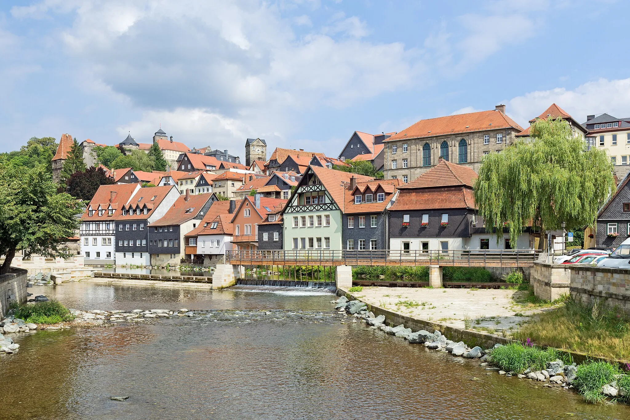 Photo showing: Der dreistufige Stadtaufbau der oberfränkischen Stadt Kronach an der Haßlach, unterhalb des Steinwehrs: Direkt am Fluss die Gebäude der Vorstadt, darüber die von einer Stadtmauer umschlossene Altstadt und im Hintergrund links die oberhalb von Kronach gelegene Festung Rosenberg.