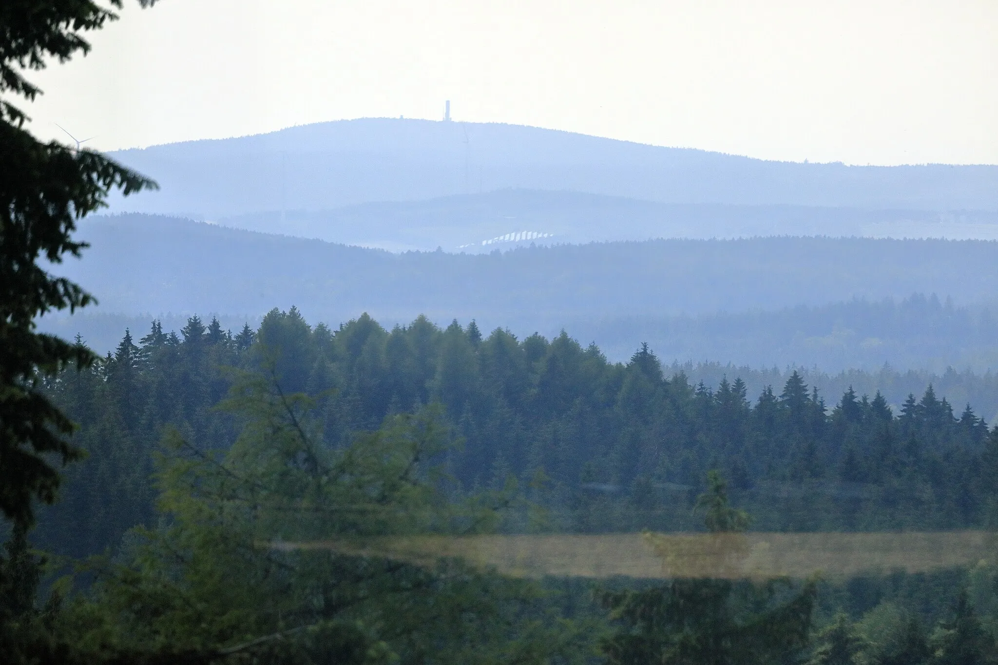 Photo showing: Knapp zwanzig Kilometer Richtung Westen, der Berg erreicht eine Höhe von 826 m und ist damit die höchste Erhebung auf der Westseite. Der knapp hundert Meter höhere Aschberg im Nordosten ist sieben Kilometer weiter entfernt und vor dem Erzgebirge unmarkant.
Der auffällige Turm war eine Abhörstation der Bundeswehr. Der eigentliche Aussichtsturm (Schönburgwarte) links daneben ragt von hier aus nur wenig über die Bäume.