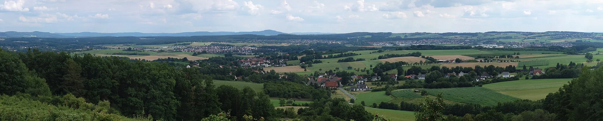 Photo showing: A panorama taken from a viewpoint close to Oberlindelbach, a village of Igensdorf, a town in northern Bavaria. It shows the following villages and towns. (Please see image annotations for locations):
Etlaswind, in the right foreground
Pettensiedel, in the center
Büg, behind Pettensiedel and to the left
Forth, to the left of Büg
Ebach, at the far left, surrounded by forest
Eckenhaid, in the center background
Eschenau, to the right of Eckenhaid, with an industrial park in the foreground
Beerbach, on the hill crest behind Eschenau
Brand, to the right of Eschenau, also with an industrial park in the foreground
Kleingeschaidt, on the hill crest behind Brand
Großgeschaidt, on the hillside to the right of Kleingeschaidt
The mountain in the center background is the Moritzberg.