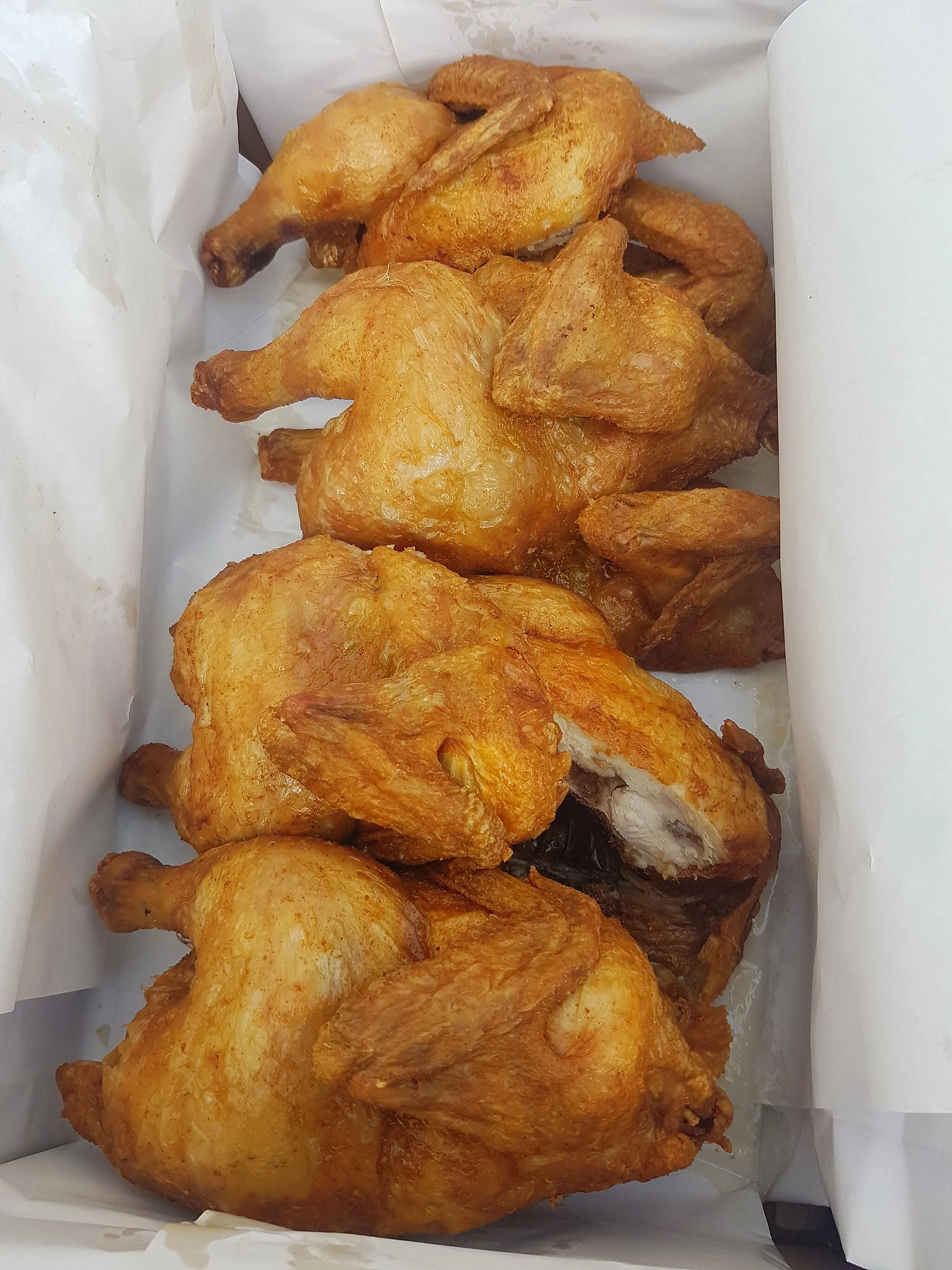 Photo showing: Four half roasted chickens in a box.