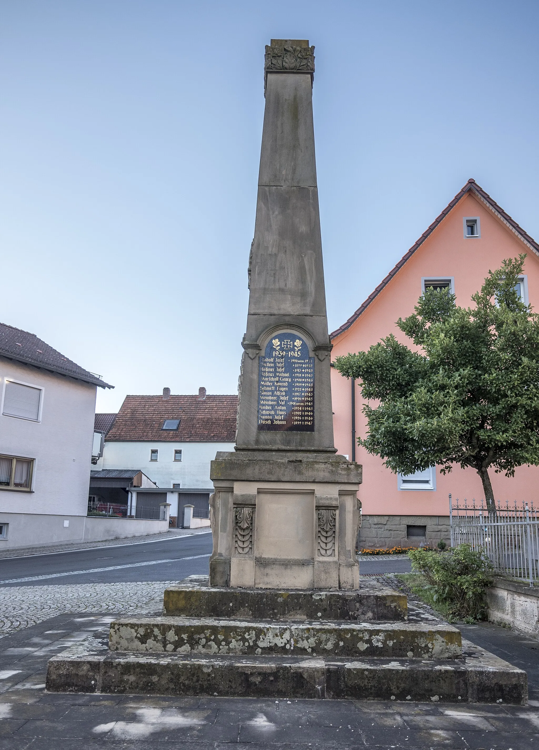 Photo showing: Kriegerdenkmal für 1870/71, ergänzt für 1914/18 und 1939/45; obeliskähnliche Pyramide mit Reliefs und Namenstafeln, Sockel mit geschwungenen Konsolen auf mehrstufigem Unterbau, Sandstein, um 1910, in Wustviel