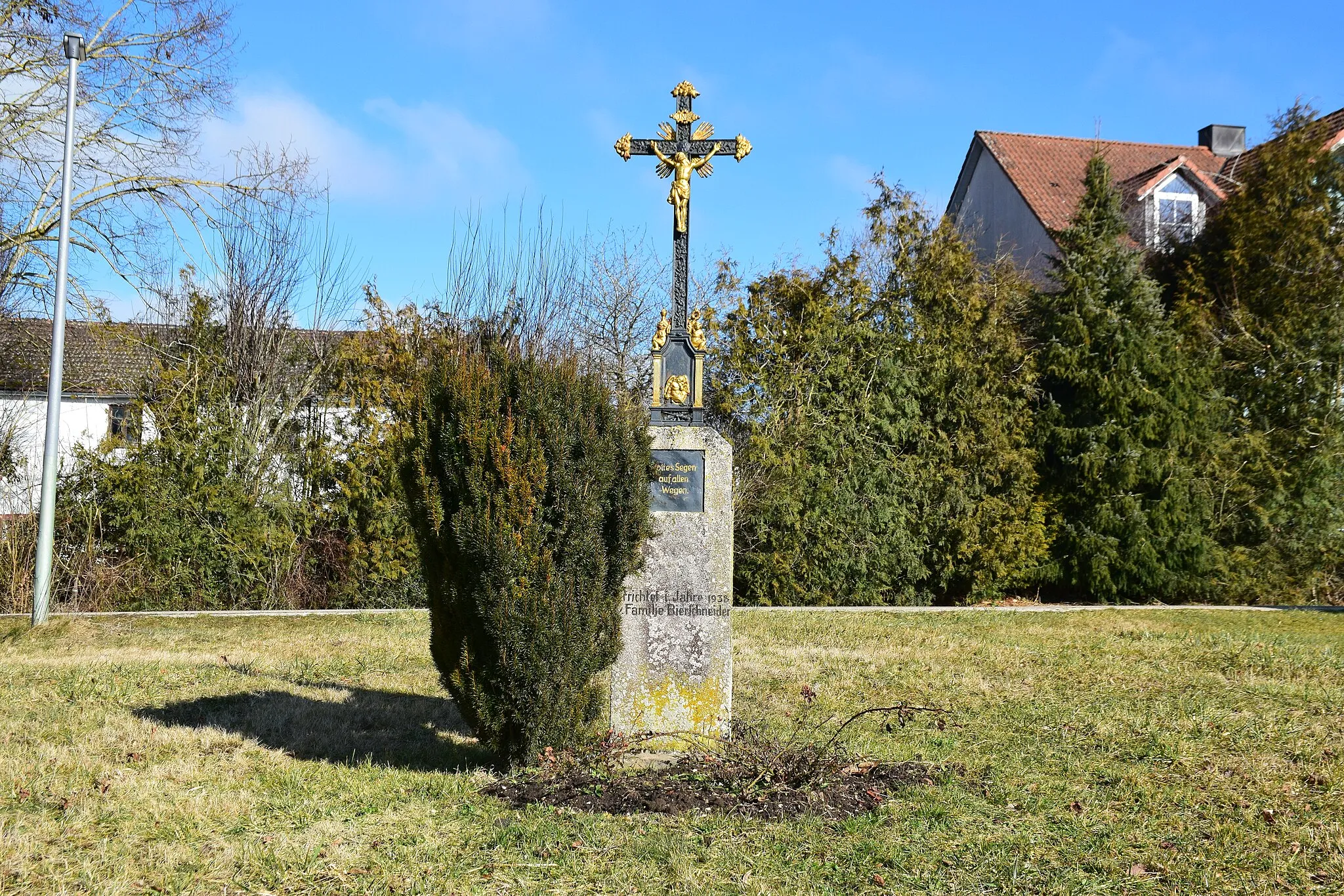 Photo showing: gusseisernes Kreuz, schwarz, Korpus und Ornamente golden, auf Kalksteinpfeiler mit Inschrift: 'Errichtet i. Jahre 1938 Familie Bierschneider', Pfeilerplatte mit Inschrift: 'Gottes Segen auf allen Wegen.'