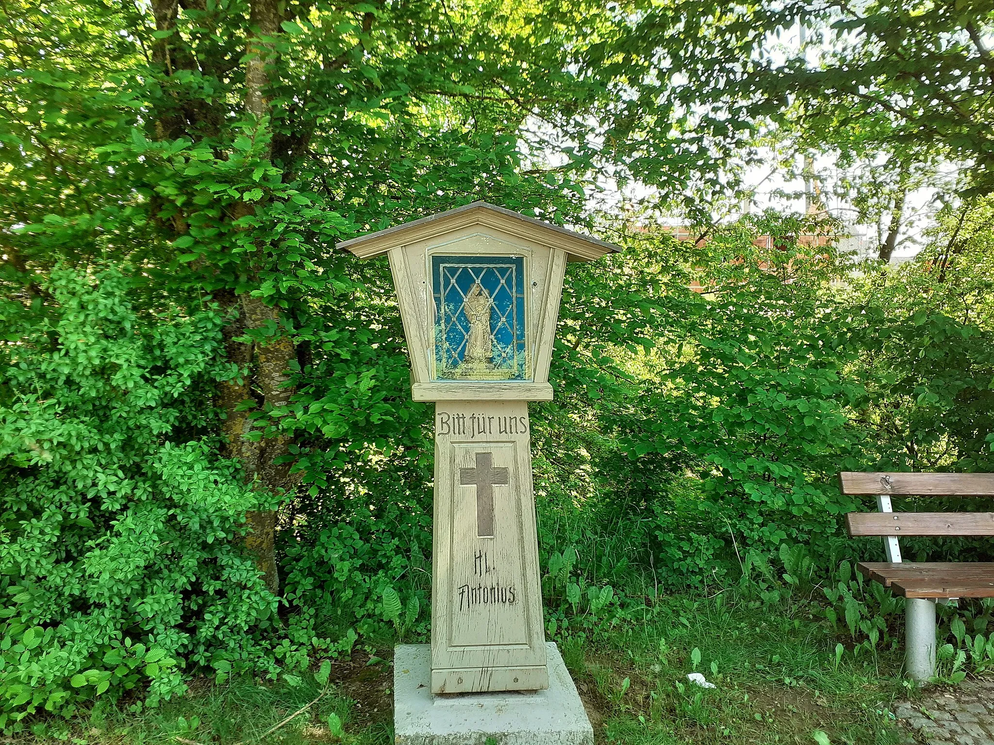 Photo showing: In Geiselhöring steht in der Verlängerung der Wilhelm-Busch-Straße am Radweg dieser Säulenbildstock aus hellem Holz an der Böschung östlich des Sportgeländes.
Die quadratische, sich nach oben verjüngende Säule ist auf einem Betonfundament errichtet. Auf der Vorderseite der Säule ist die eingeschnitzte Schrift zu lesen:
"Bitt für uns Hl. Antonius".
In einer genuteten Kartusche ist farblich dunkler ein breites Kreuz geschnitzt.
Der auskragende Tabernakelaufsatz ist aus profilierten Brettern und Leisten geschreinert. Das flache Satteldach ist mit  Kupferblech eingeschlagen. In einem verglasten und vergitterten, rechteckigen Schrein steht eine Statuette des heiligen Antonius von Padua in Mönchskutte und Tonsur, der das Jesuskind auf dem Arm trägt.
Auf der Rückseite sind der Name Anton Wild, der das kleine Denkmal zu Ehren seines Namenspatrons errichtet hat und das Errichtungsjahr in die Säule eingeschnitzt. Dort steht zu lesen:

A. Wild 1997