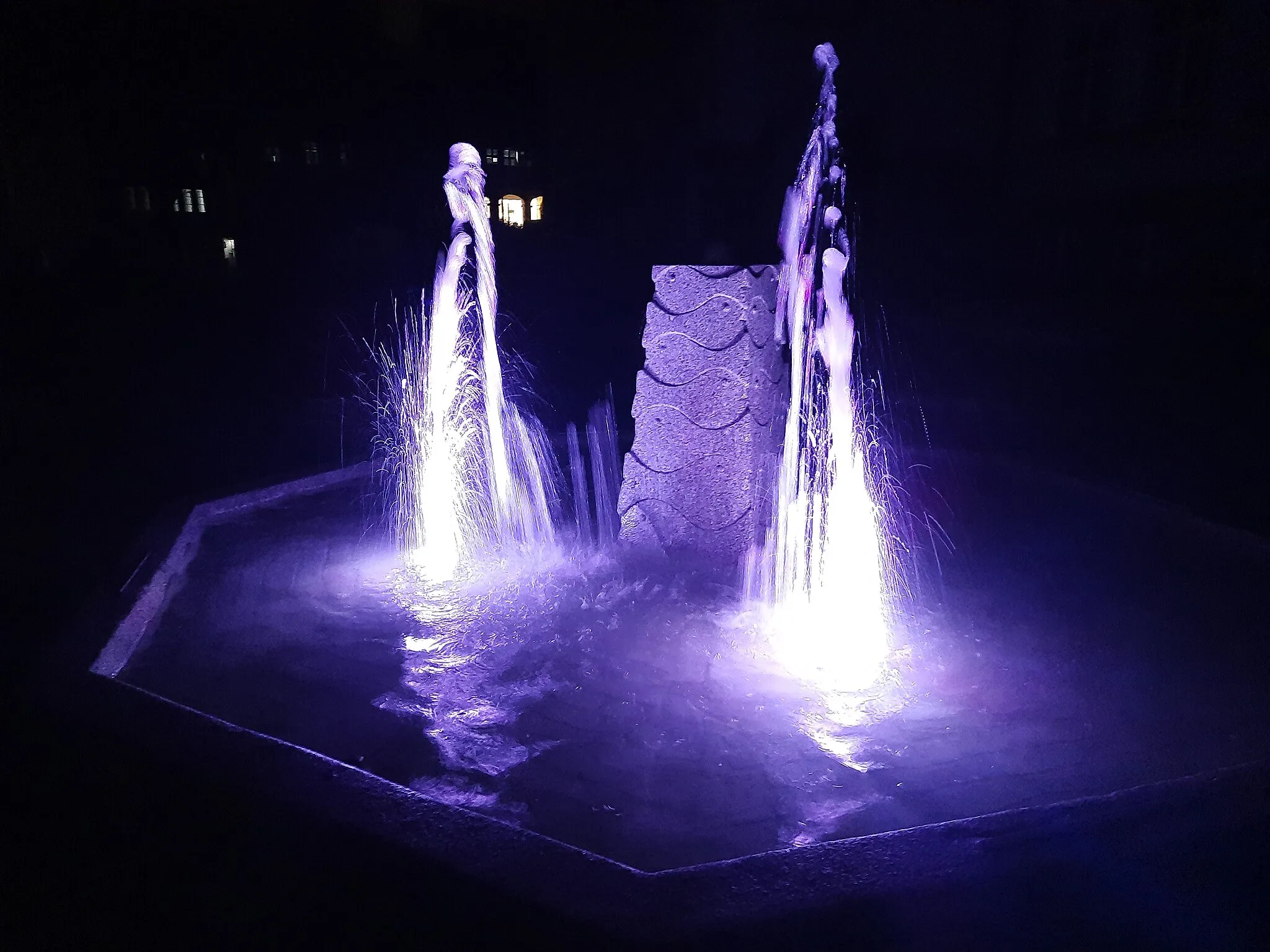 Photo showing: Fischbrunnen am Landratsamt Tirschenreuth bei Nacht – Lichtshow: Lila – Der Brunnen liegt unmittelbar an der Durchgangsstraße St 2167 und besteht aus 4 Wasserfontänen welche abwechselnd Wasser hörbar ansaugen und spritzen. Bei Dunkelheit wird das Wasser des Brunnens mit verschiedenen Farben angestrahlt.