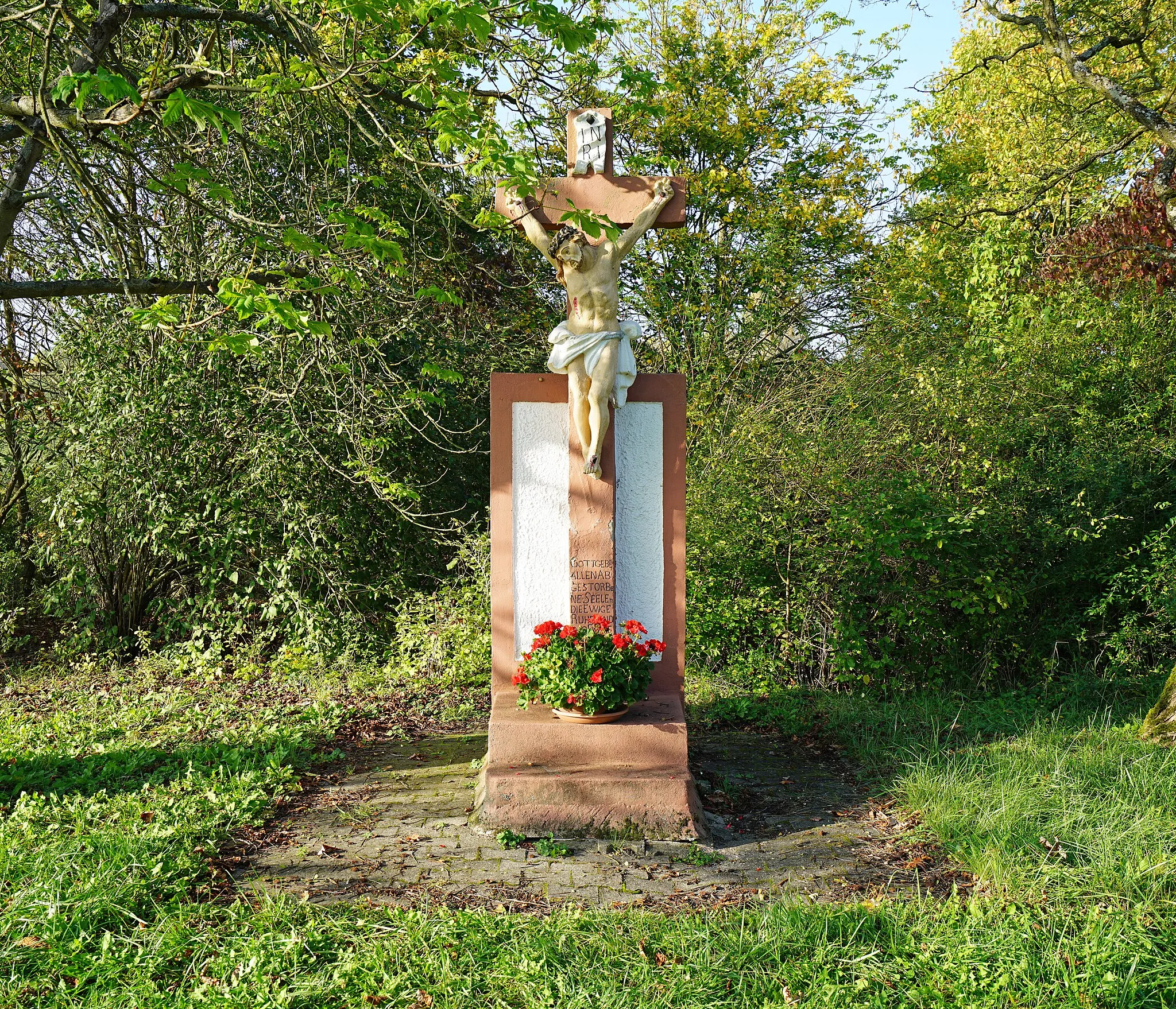 Photo showing: Unter Denkmalschutz stehendes Feldkreuz auf der ehemaligen Gemarkung der Gemeinde Rudelsheim auf der heutigen (2017) Gemarkung der Ortsgemeinde Ludwigshöhe in Rheinhessen. Am 25. August 1822 erfolgte die Grundsteinlegung von Ludwigshöhe, deren Ortsmitte heute (2017) etwa zwei Kilometer westlich dieses Feldkreuzes liegt. Unter dem Kruzifix steht: „Gott gebe allen abgestorbene Seelen die ewige Ruhe und das ewige Licht leichte ihnen o Herr lasz sie ruhen in Frieden Amen“