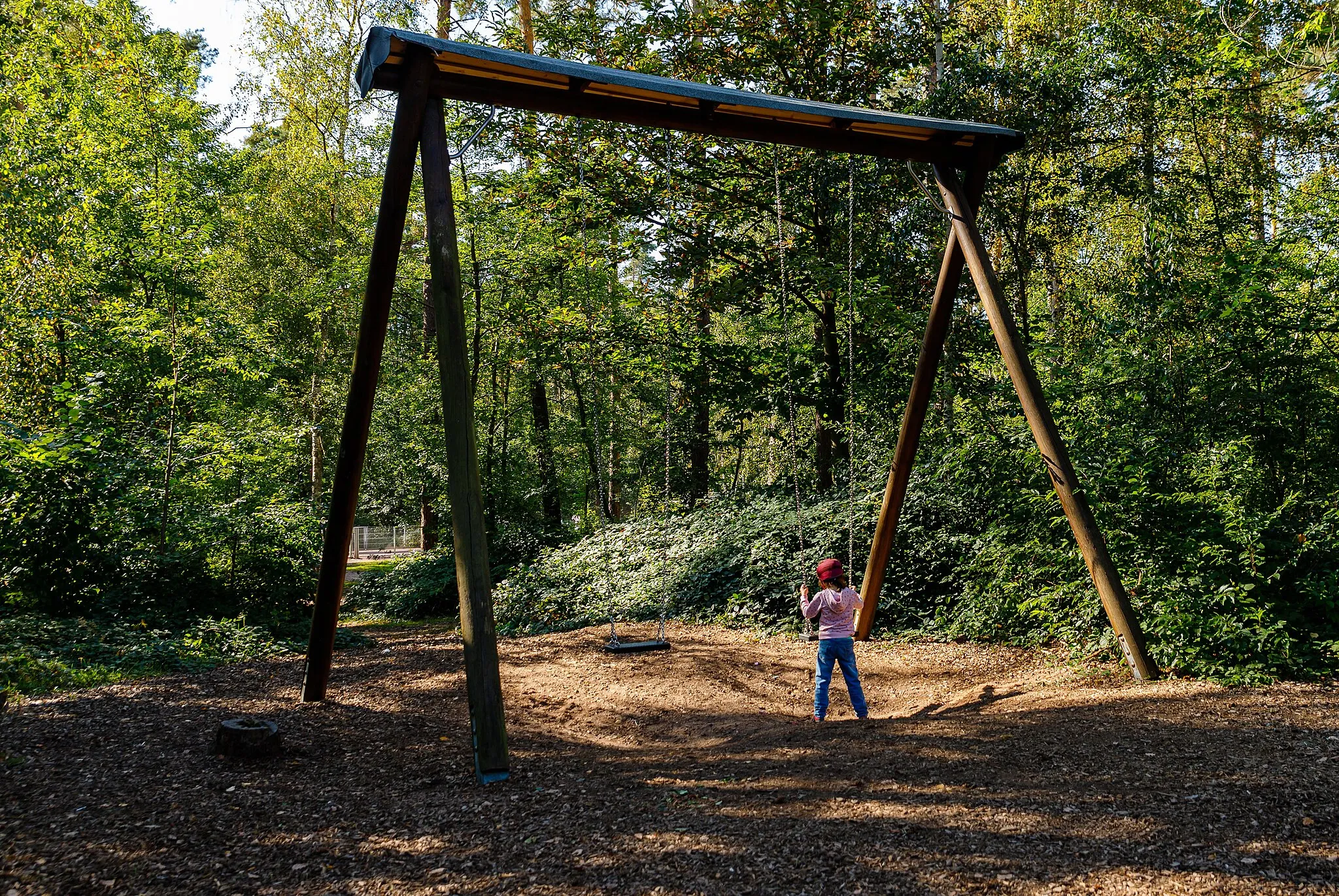 Photo showing: Lonely child on swing at adventure playground