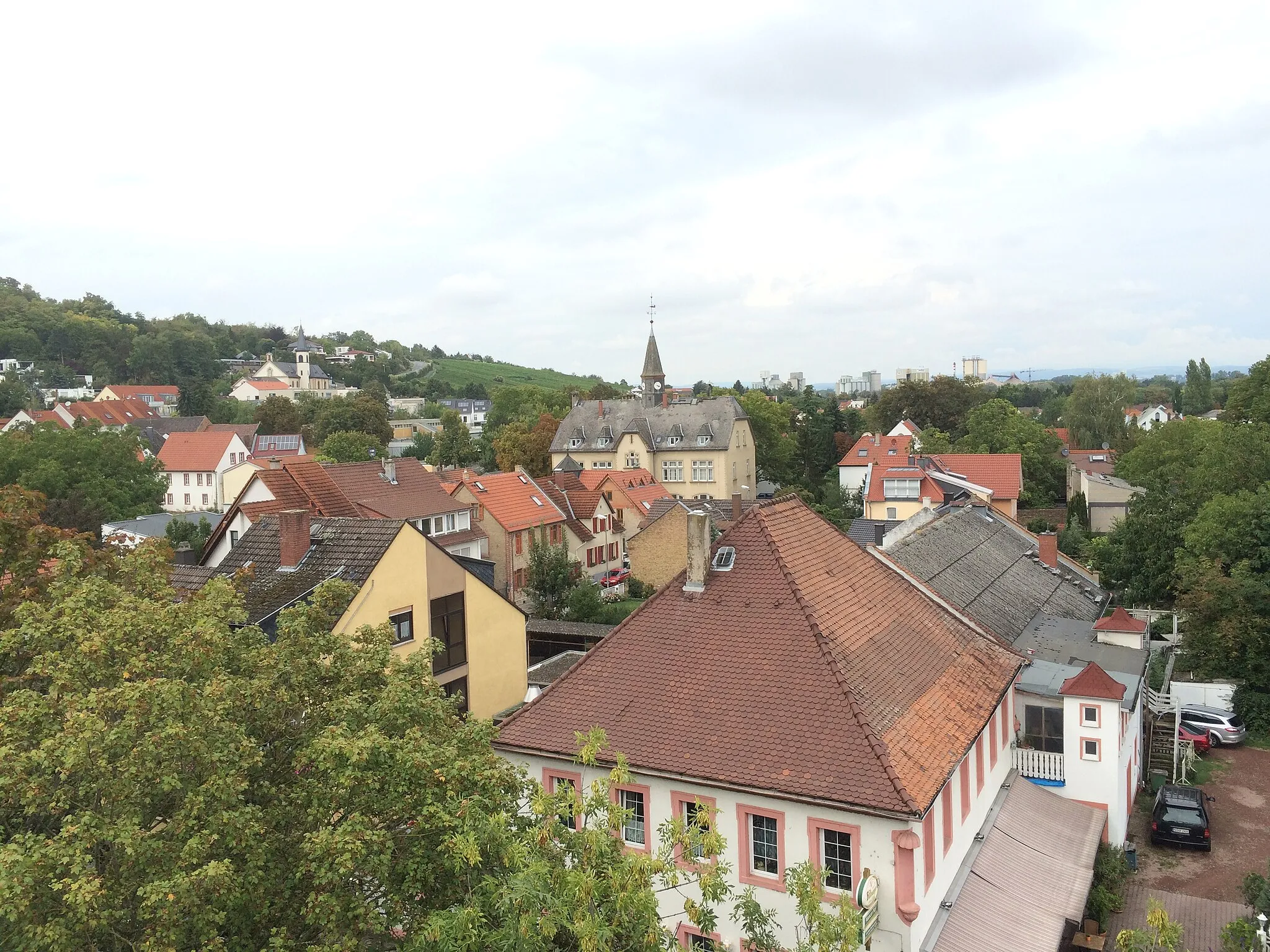 Photo showing: Mainz-Laubenheim, im Vordergrund das historische Gasthaus “Mainzer Hof”, im Hintergrund das Zementwerk Weisenau. Sicht auf Laubenheim in Richtung Norden aus Fahrgeschäft. Links oben katholische Kirche „Mariä Heimsuchung“, mittig das alte Schulhaus.