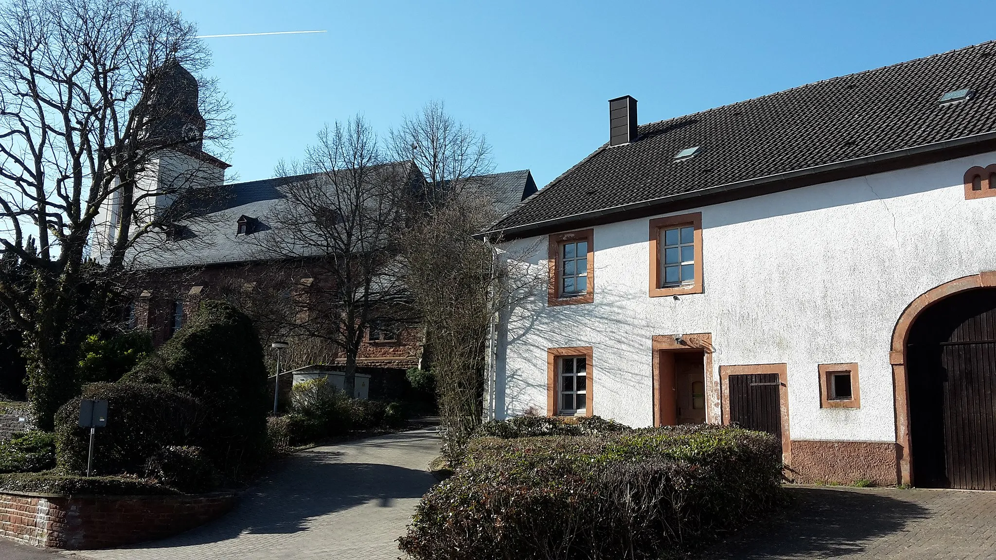 Photo showing: Zwei der ausgewiesenen Kulturdenkmäler in Greimerath:
Links Pfarrkirche St. Nikolaus. Rechts: Ein typisches Hochwälder Quereinhaus