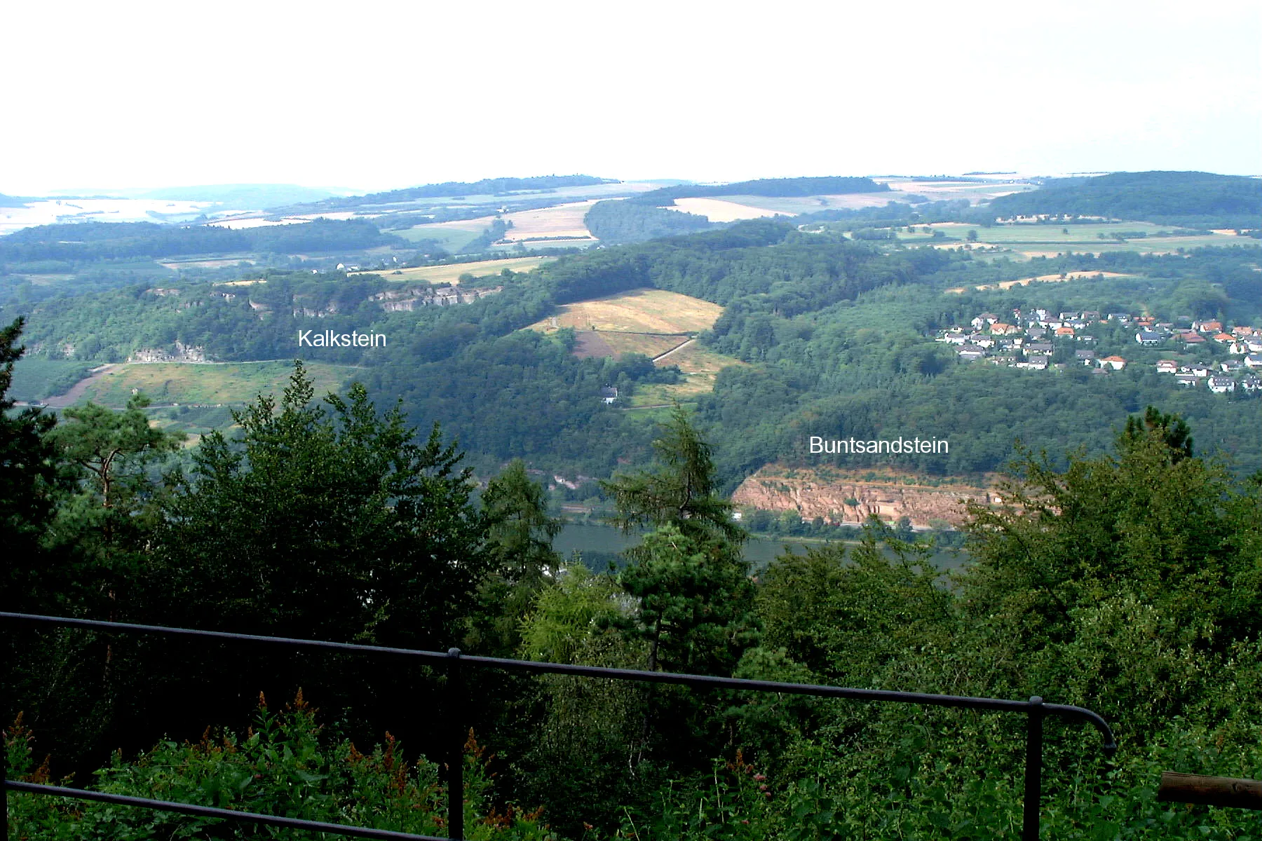 Photo showing: Blick vom Lieschenberg auf das linke Moselufer bei Igel, rund einen Kilometer oberhalb der Saar-Mündung. Am gegenüberliegenden Ufer und in den Hängen unmittelbar oberhalb sind Schichten des ?mittleren und oberen Buntsandsteins und des mittleren und oberen Muschelkalks aufgeschlossen, aufgrund der sogenannten Igeler Verwerfung unmittelbar nebeneinander.