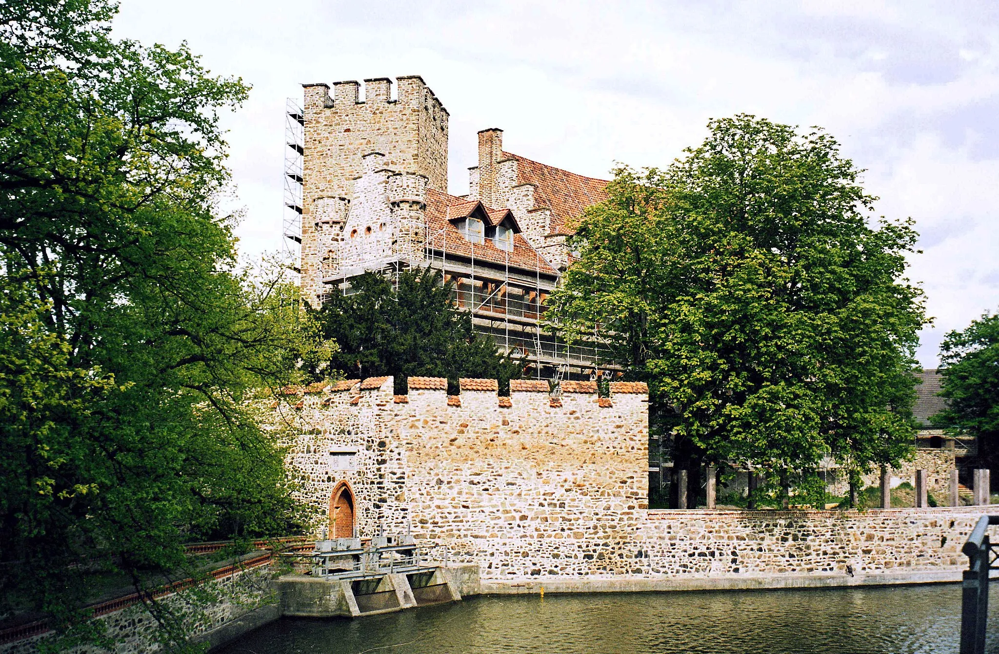 Photo showing: 02.05.2003   39345  Flechtingen, Lindenplatz: Wasserburg/Schloß (GMP: 52.331118,11.238324). Die Wasserburg Flechtingen war der ursprüngliche Stammsitz der Adelsfamilie Schenck von Flechtingen. Die ältesten Gebäudeteile entstanden um 1300, zu ihnen gehören die Ringmauer, der Palas und der Bergfried. Erste große Veränderungen wurden 1483 mit der Verlagerung der Burg nach Westen vorgenommen. Ende des 15. Jahrhunderts wurden spätgotische Bauelemente hinzugefügt, 100 Jahre später erhielt die Anlage Veränderungen im Renaissance-Stil. Um 1600 wurde die ehemalige Zugbrücke durch eine Dammzufahrt ersetzt. Bei den letzten Umbauten zwischen 1840 und 1890 erhielt das Wasserschloß sein historistisch-neugotisches Aussehen. Nach der Enteignung des Schlosses diente es 1945 zunächst als Flüchtlingsunterkunft. Danach wurde es als Genesungsheim genutzt, ehe es 1958 von den Grenztruppen der Volksarmee übernommen wurde. Von 1964 bis 1993 war das Schloß ein Altersheim.                                                                                                                                                                   [F20030502A01A.jpg]20030502520NR.JPG(c)Blobelt