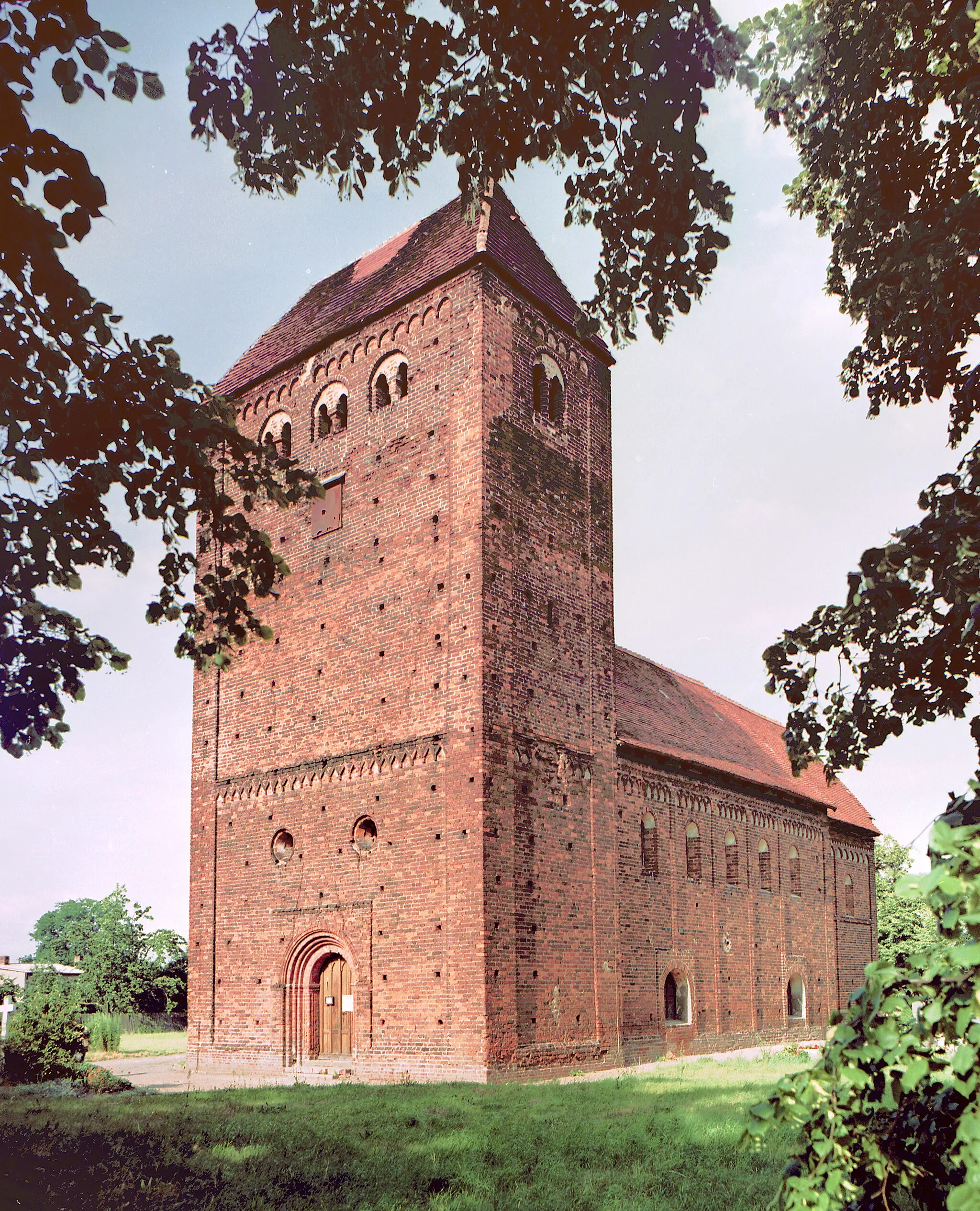 Photo showing: 18.07.1986  DDR-3281  [39319]  Redekin (Jerichow): Die evangelische Dorfkirche (GMP: 52.466650,12.075500) Redekin ist eine romanische Backsteinkirche aus der Zeit um 1200. Sie ist eine Saalkirche und gilt als Musterbeispiel für eine vierteilige romanische Dorfkirche. Im Westbau findet sich ein aufwändiges rundbogiges Stufenportal in einer rechteckigen Wandvorlage, über dem zwei Oculi angeordnet sind. Der Westquerturm ist mit einem Walmdach gedeckt, auf dem eine 1974/75 beseitigte achteckige Laterne als Bekrönung angeordnet war.                                                                                                        [R19860718D01.TIF]19860718600NR.JPG(c)Blobelt