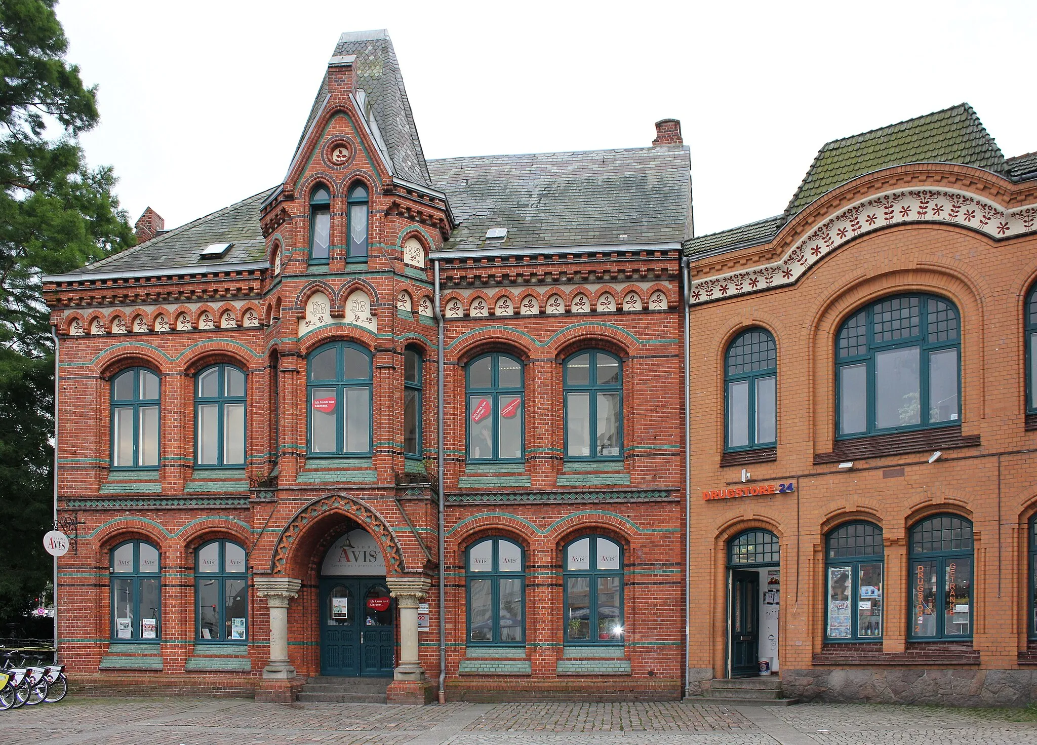 Photo showing: Flensburger Gebäude in der Schiffbrückstraße am Schiffbrückplatz (beziehungsweise auch Willy-Brandt-Platz genannt); zur linken Seite: Gebäude Schiffbrückstraße 8 (erbaut 1883 gemäß Inschrift zur rechten des kleinen Turmes), in in dem die Flensborg Avis zu finden ist und welches die Polizeistation in der Serie Da kommt Kalle darstellt.