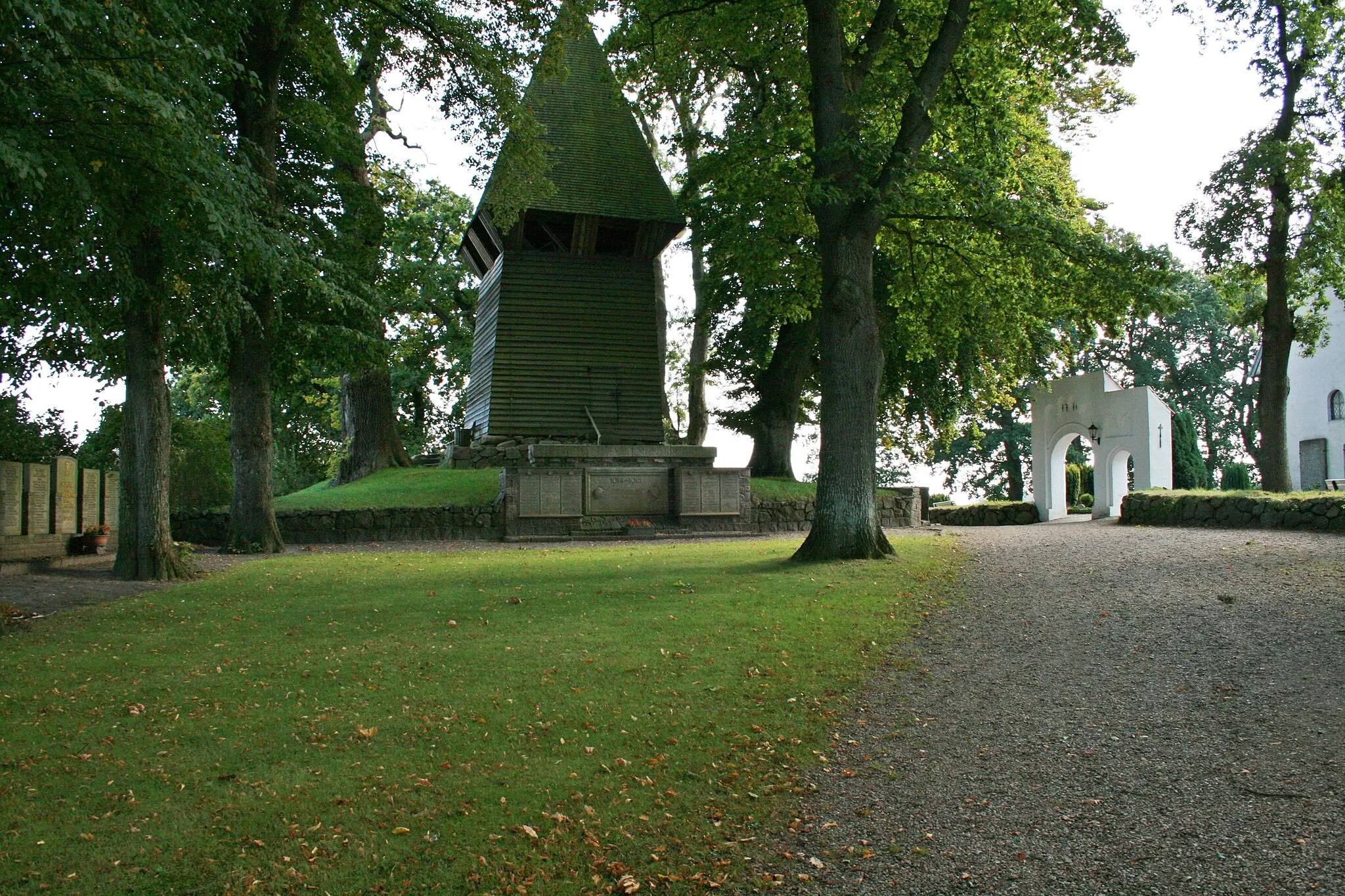 Photo showing: Der hölzerner Glockenturm (Glockenstapel) in Ulsnis, rechts das östliche Eingangstor zum Friedhof aus dem Jahr 1761 - Aufnahme vom September 2007.