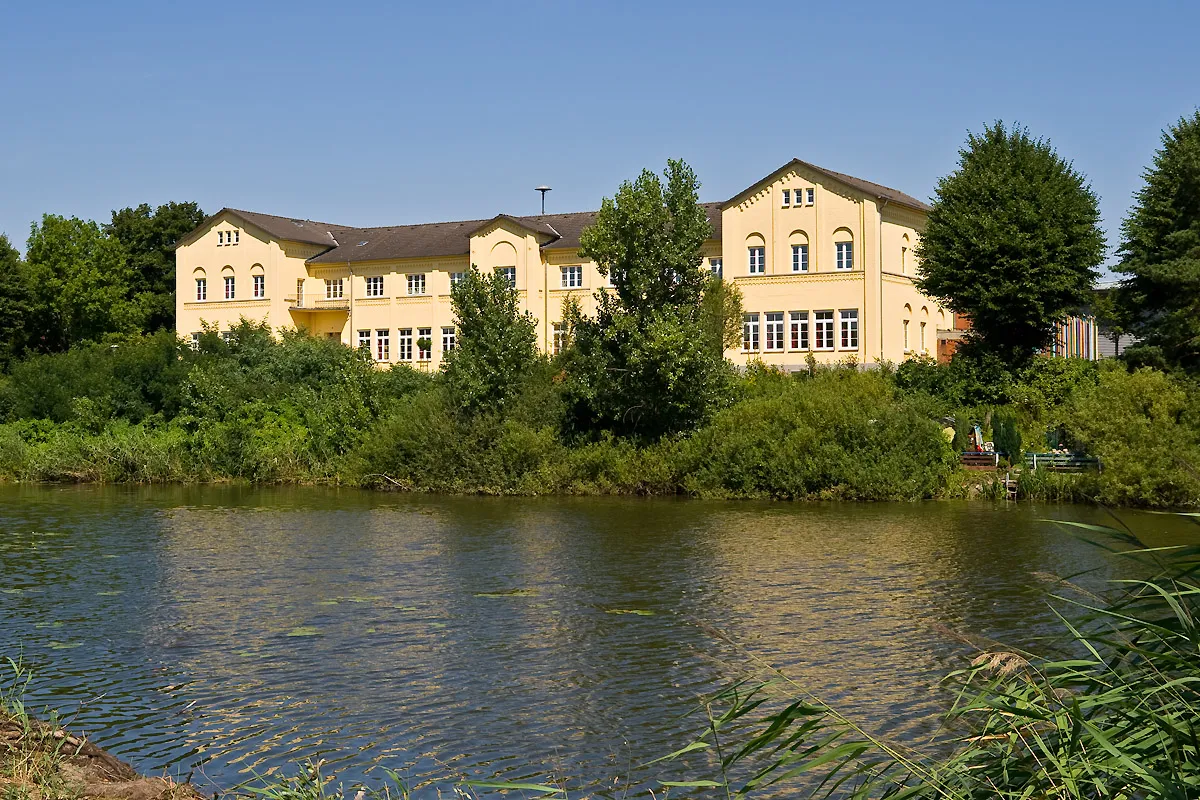 Photo showing: Die Grundschule in Hohnstorf (Elbe) befindet sich seit 1959 im ursprünglichen Empfangsgebäude des Bahnhofes Hohnstorf. Der Bahnhof wurde zwischen 1862 und 1864 als Zoll- und Endbahnhof der Zweigbahn Lüneburg–Hohnstorf an der Lauenburg-Hohnstorfer Elb-Traject-Anstalt gebaut. Das Bahnhofsgebäude war zur damaligen Zeit nach dem Bahnhof Hannover das zweitgrößte der Königlich Hannoverschen Staatseisenbahn. Das ehemalige Bahnhofsgebäude, der davor befindliche See, der beim Bau der Trajekt-Anstalt ausgehoben wurde, und ein noch vorhandenes Teilstück des Bahndamms stehen unter Denkmalschutz.